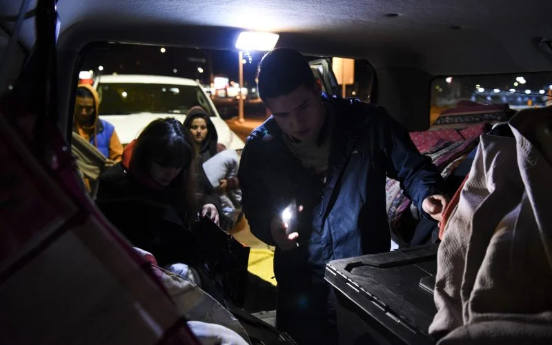 Two volunteers with the Hellfighters Ministry look through bins of donated clothing in the back of a van on February 2, 2019. Two homeless people wait patiently behind them, hoping they will find a jacket, pants, or underwear in their size. /Photo by Celia Raney/ NM News Port