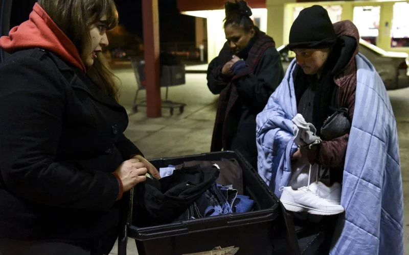 A homeless woman looks through a box of jeans with Jacqui Boyd on Feb. 2, 2019, when the Hellfighters Ministry makes their second stop of the night. /Photo by Celia Raney/ NM News Port