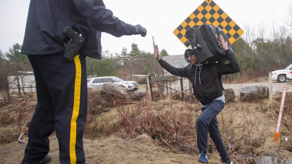 An RCMP officer warns a man to cross at the legal border crossing or he will be arrested at the border from New York into Canada on Wednesday, March 8, 2017 in Hemmingford, Quebec. (THE CANADIAN PRESS/Ryan Remiorz)