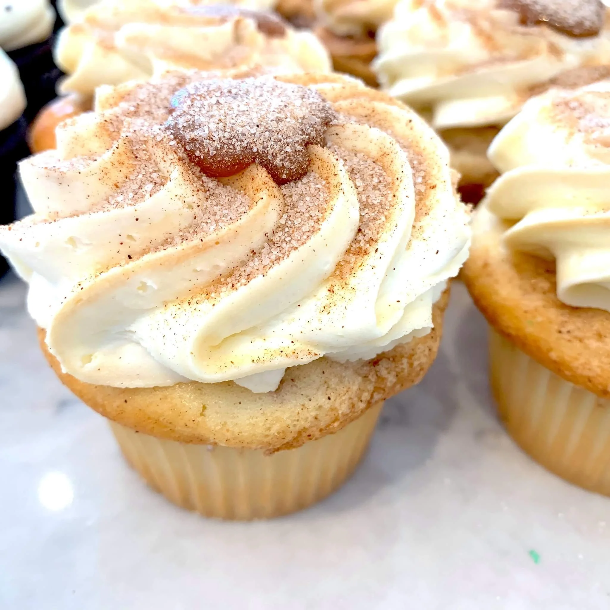 Cupcake topped with cream cheese frosting and sprinkled with cinnamon and sugar.