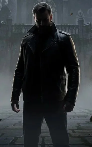 A man wearing a black leather jacket standing in a foggy, dark outdoor setting with a railing and trees in the background.
