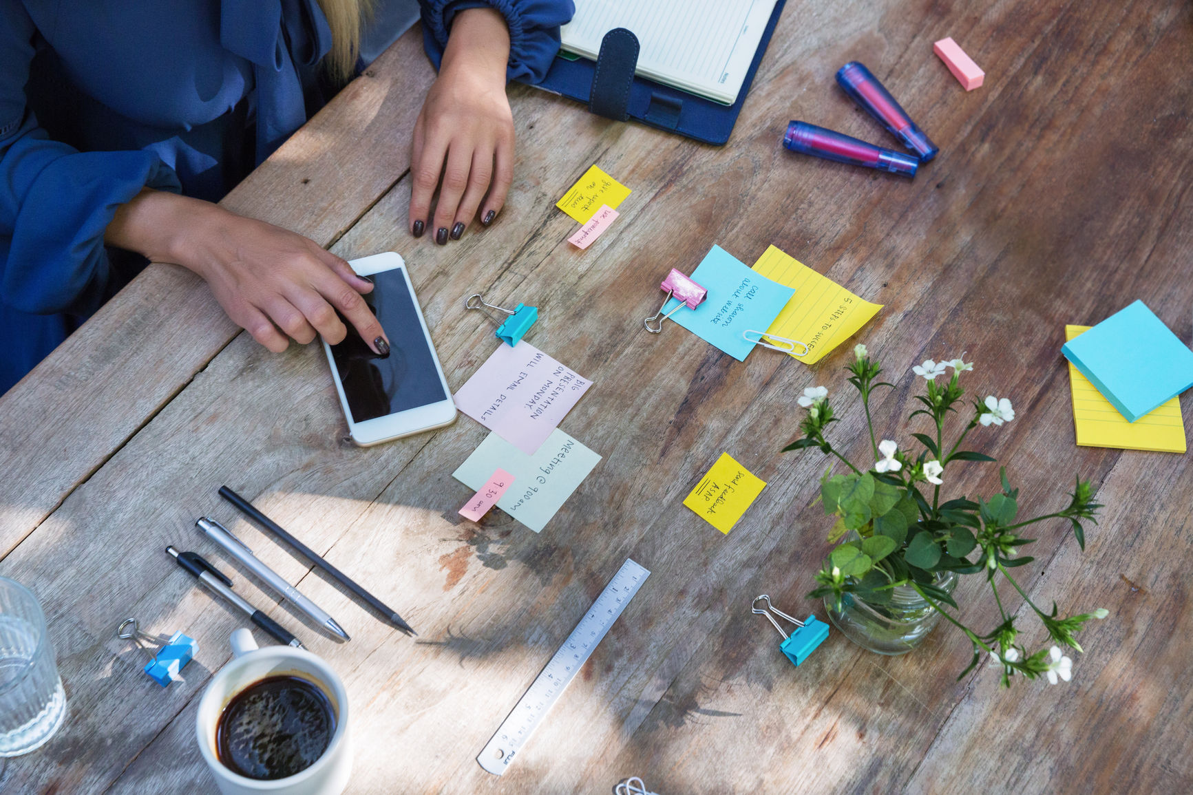 Top View Of A Desk With Hands And Notes And Phone On It