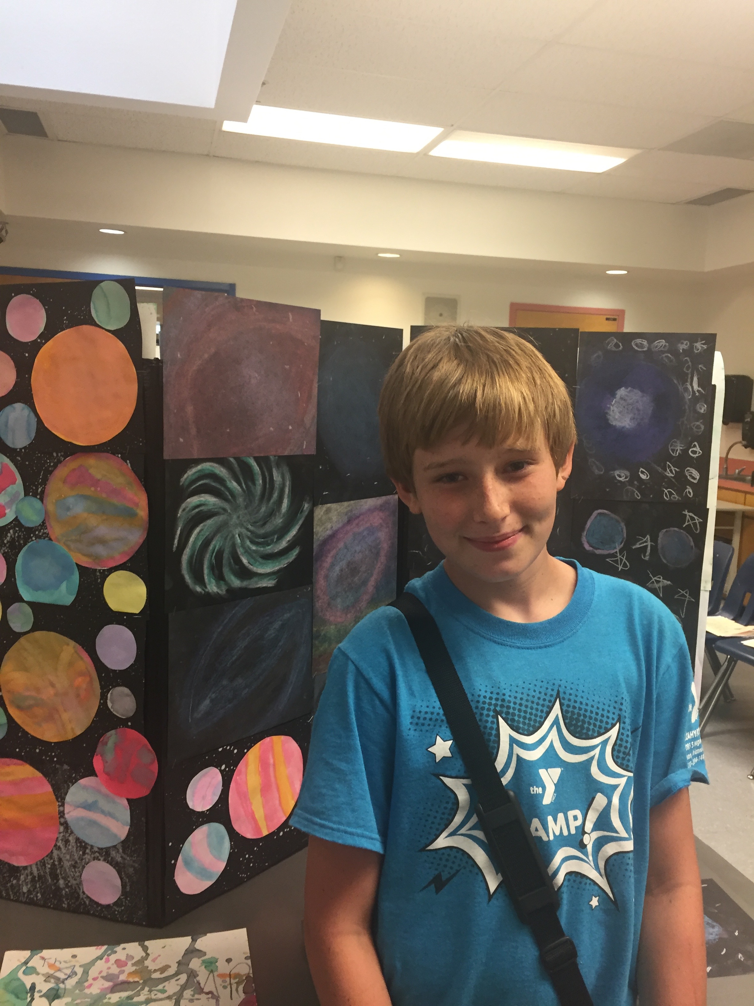 Young artist posing next to his artwork (Tucson YMCA)