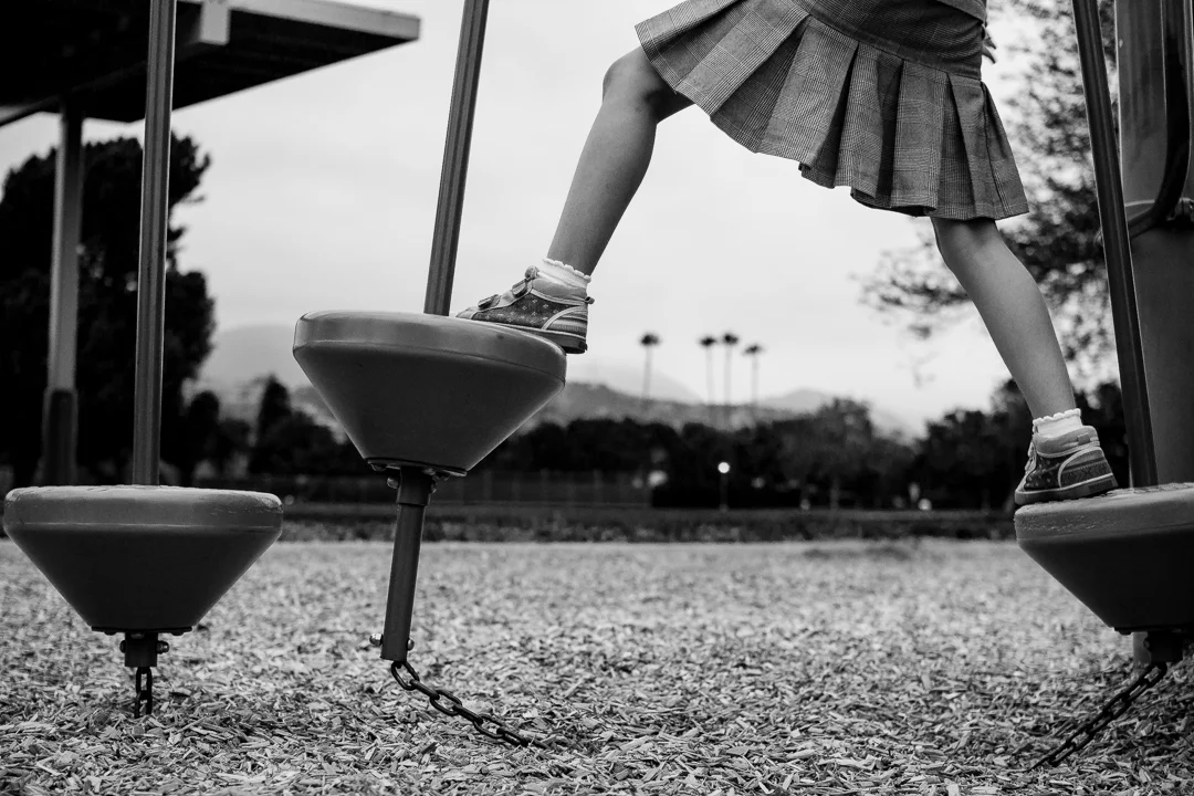 Black and white photo of girl climbing on the playground equipment in Claremont, CA by Erica Faith Walker