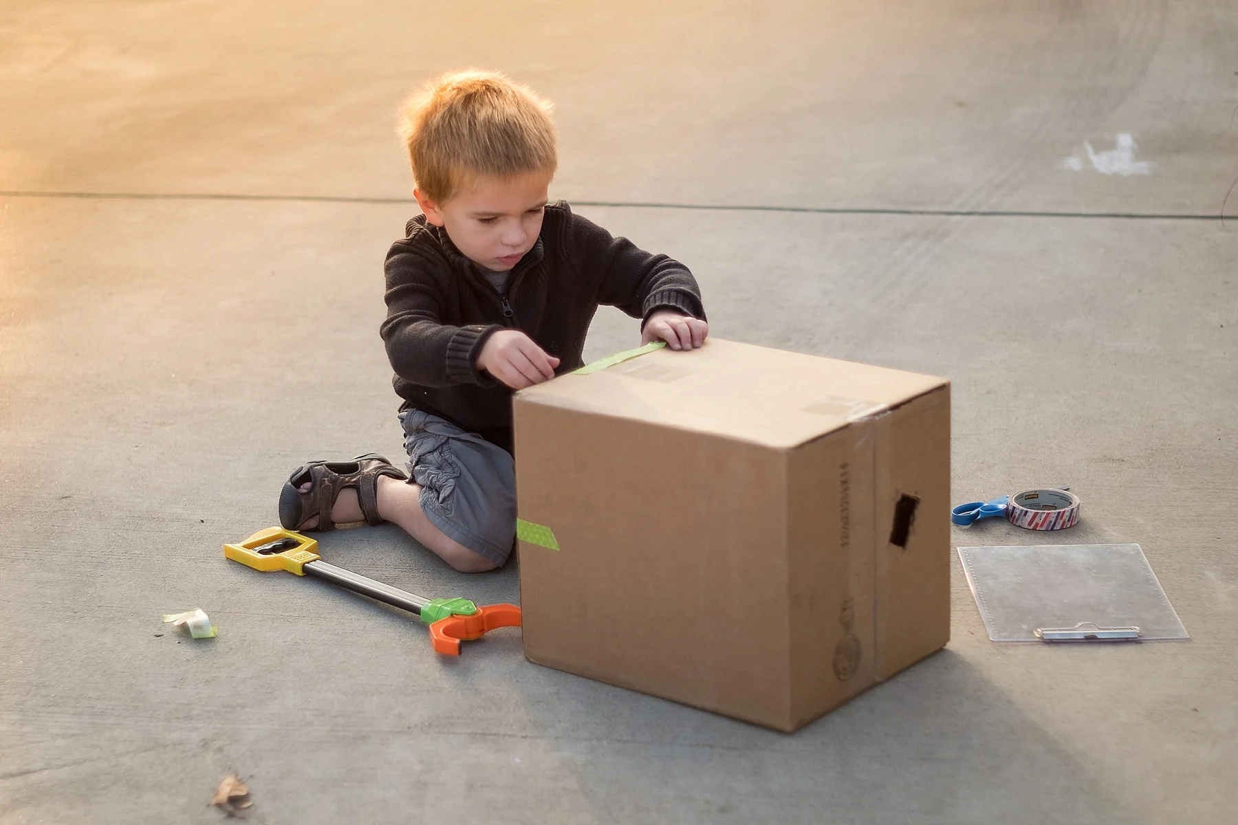 Erica Faith Walker takes a golden hour photo of a boy playing with a box in Claremont, CA.