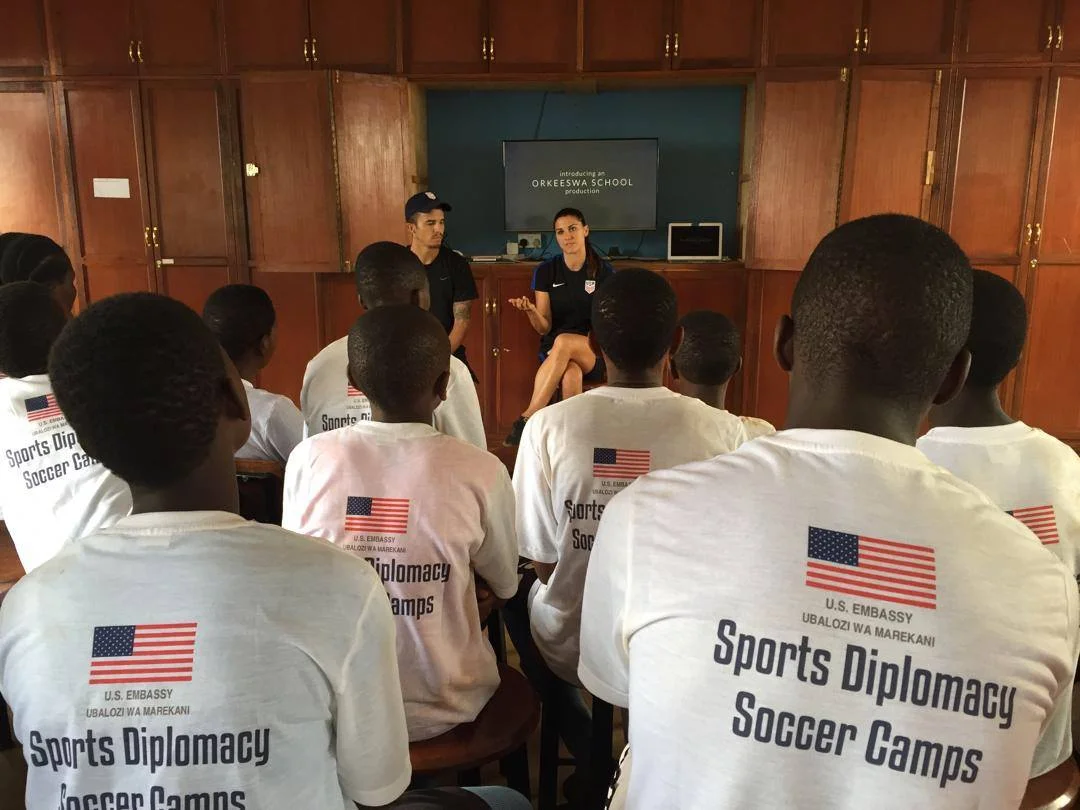 Sports Envoys and U.S. Women’s National Team member, Alex Morgan, and Orlando City player Servando Carrasco demonstrate speak with youth in Tanzania. 2017. 