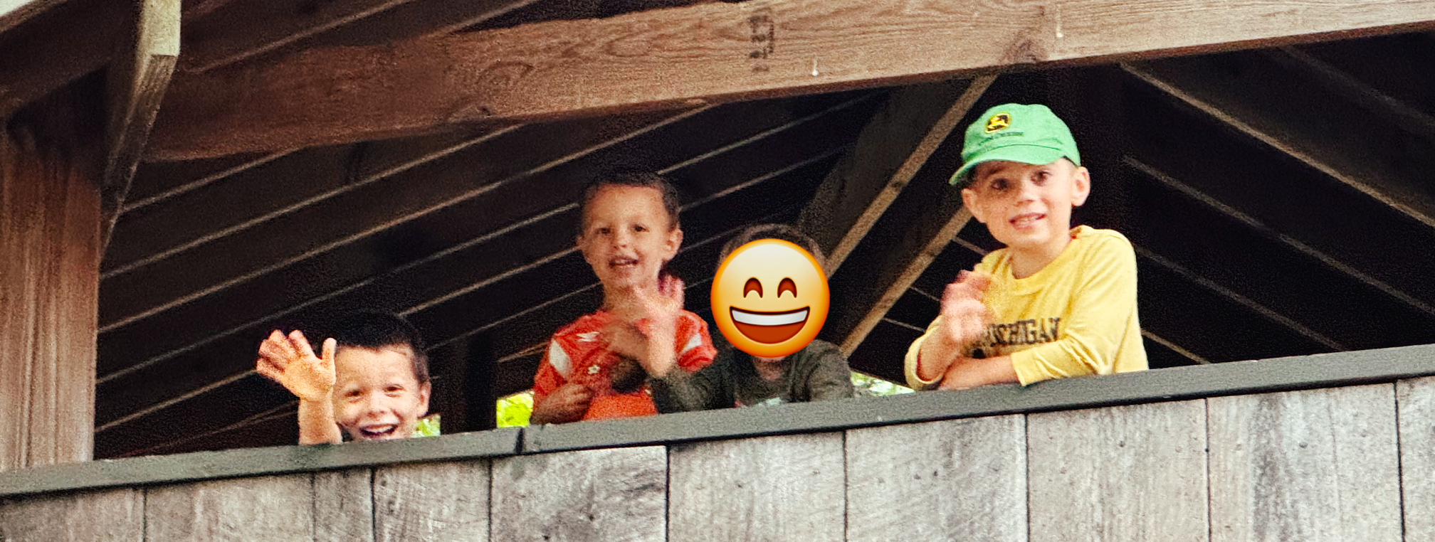 four children smiling and waving