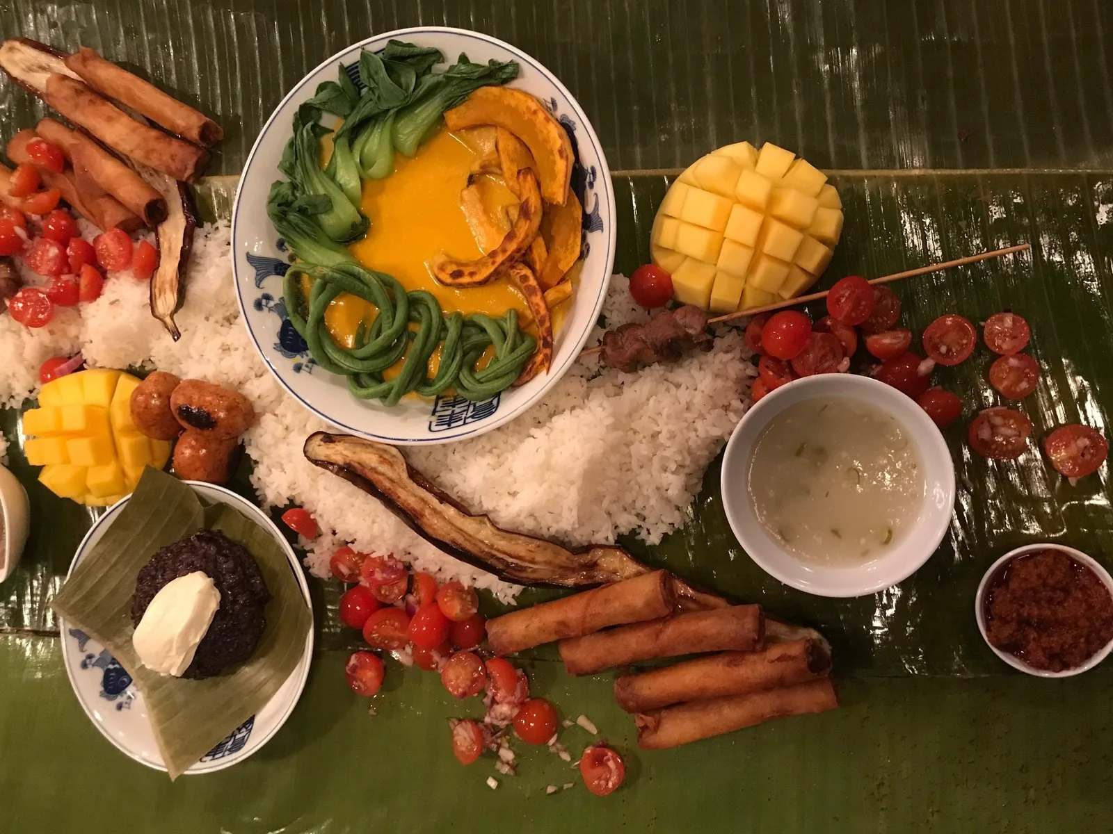 A kamayan is a communal-style Filipino feast, composed of colorful arrays of food that are usually served on banana leaves and eaten without utensils. / Bettina Makalintal for NPR