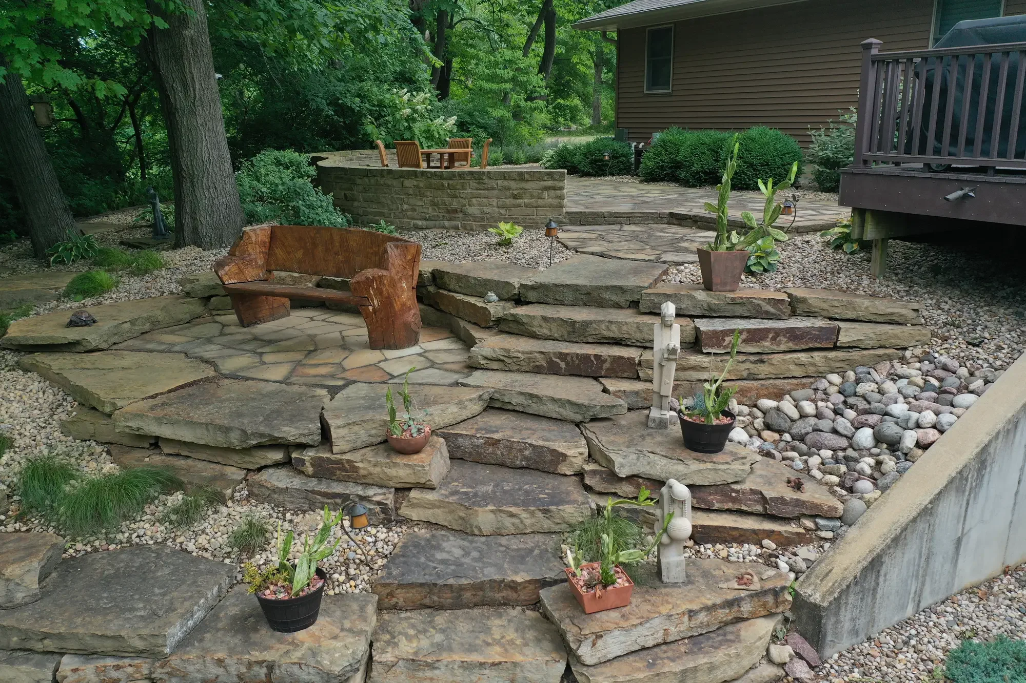 Multi-level flagstone patio with natural wood bench and raised stone seating wall by Green View in Central Illinois