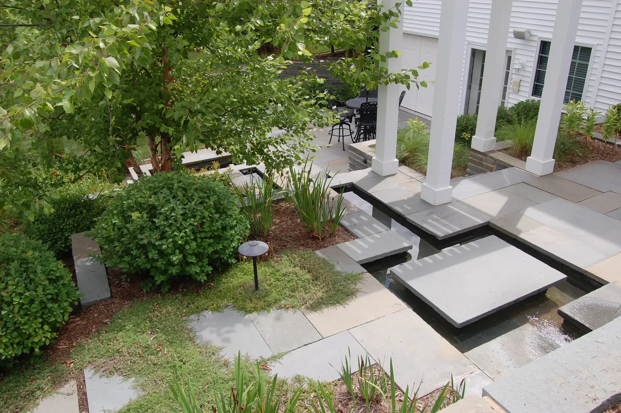 Angled aerial of pool with spa, geometric turf-and-paver surround, chaise lounges, and upper entertaining patio at Geometric Oasis Retreat by Green View in Illinois