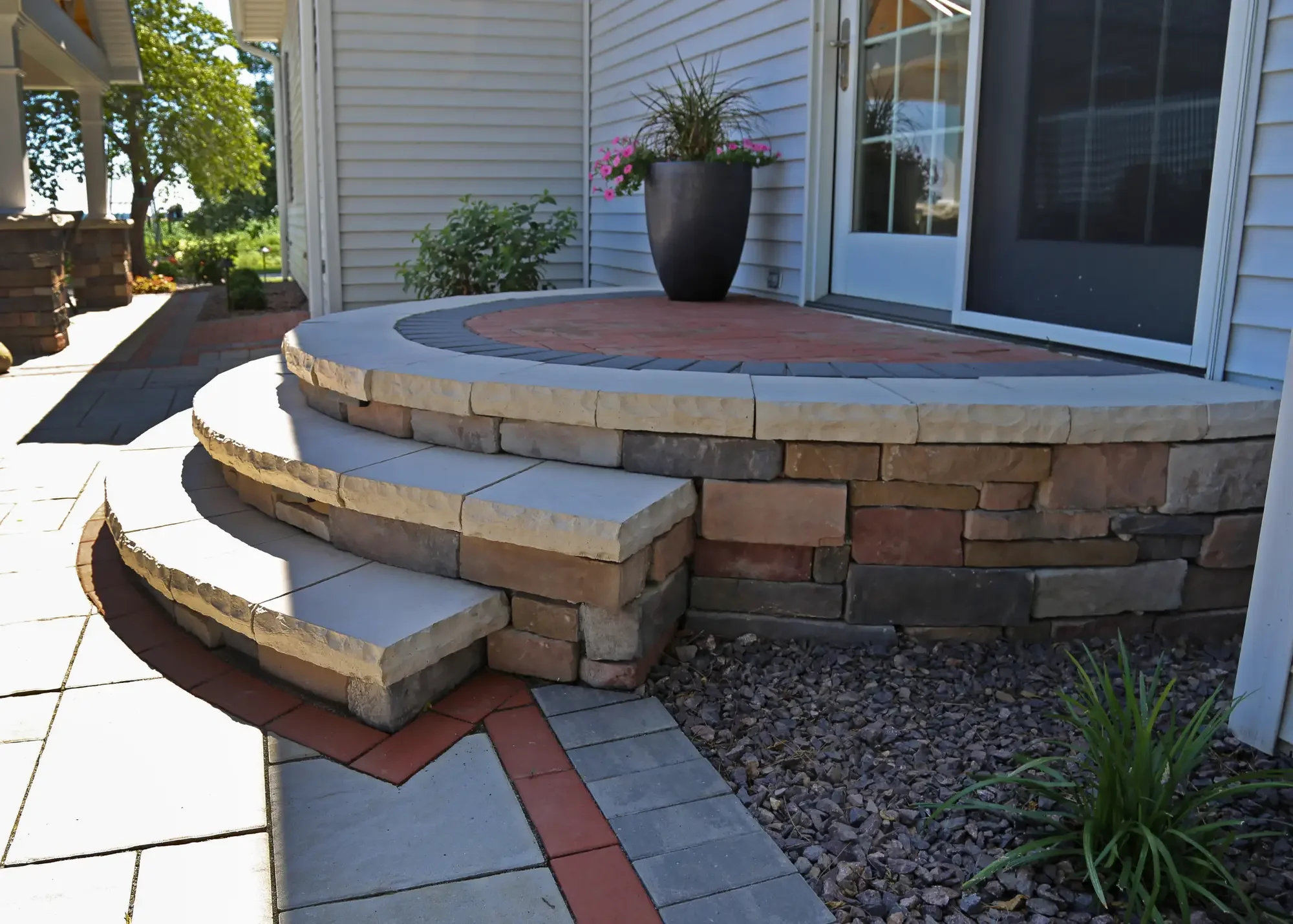 Curved stone retaining wall with tiered steps and two-tone paver landing at The Prairie Pavilion by Green View in Illinois