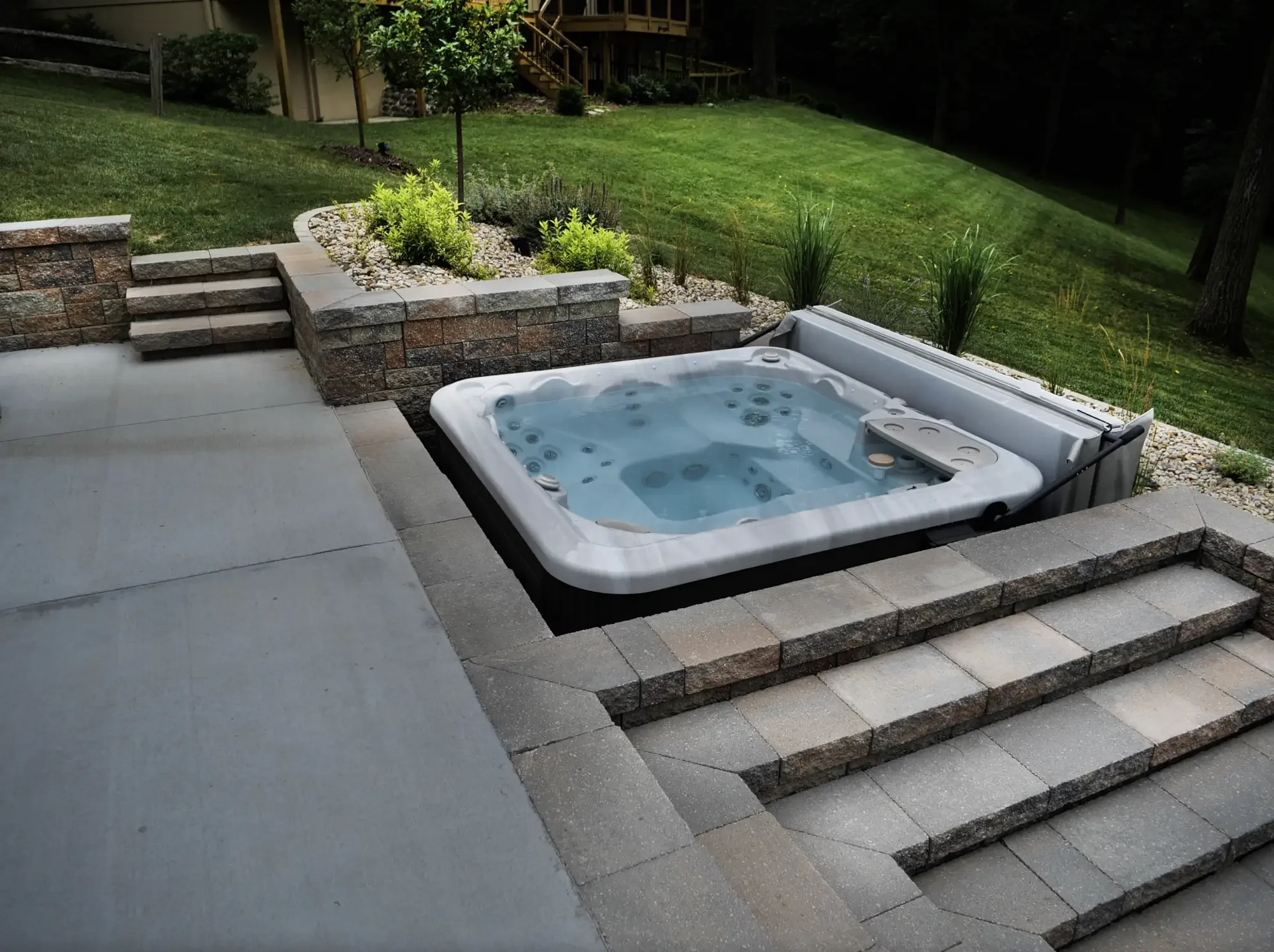 Inset hot tub with stone retaining wall steps and perennial planting beds at The Amphitheater by Green View in Illinois