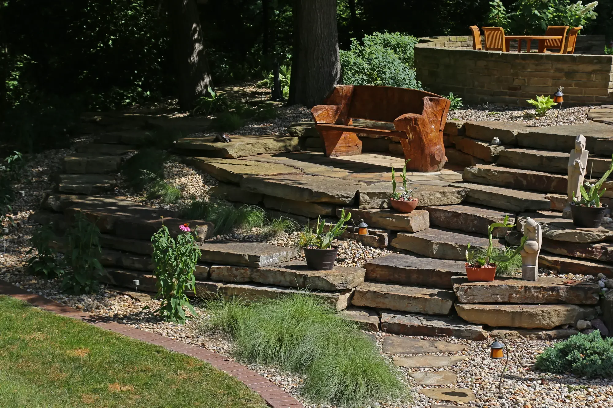 Natural stone steps bordered by ornamental grasses and echinacea leading to raised flagstone patio by Green View in Central Illinois