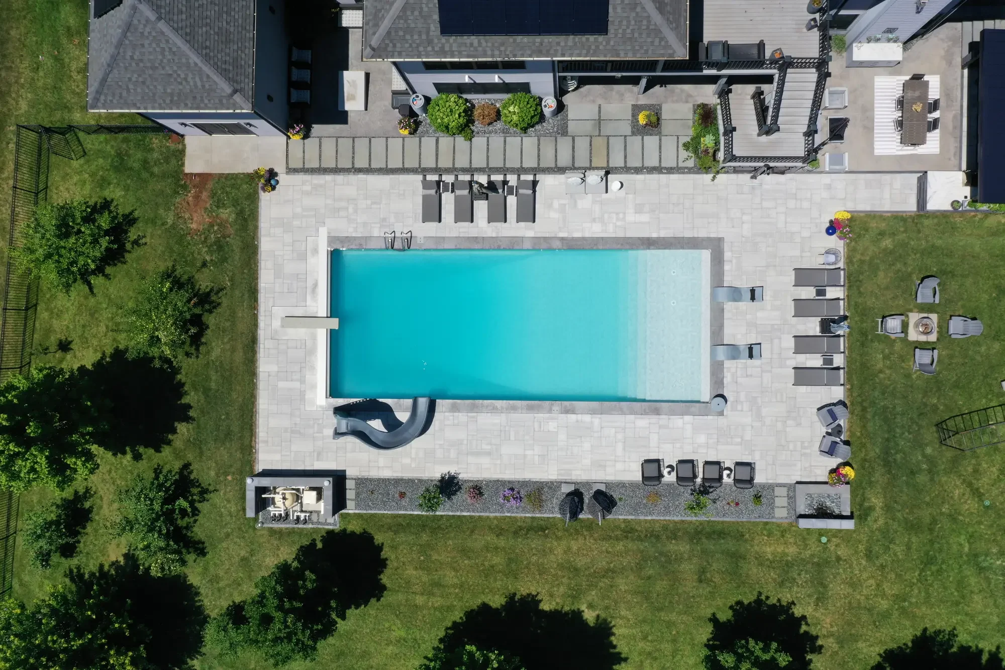 True overhead aerial of rectangular pool, large-format paver surround, and modern pergola at Slate and Steel by Green View in Illinois