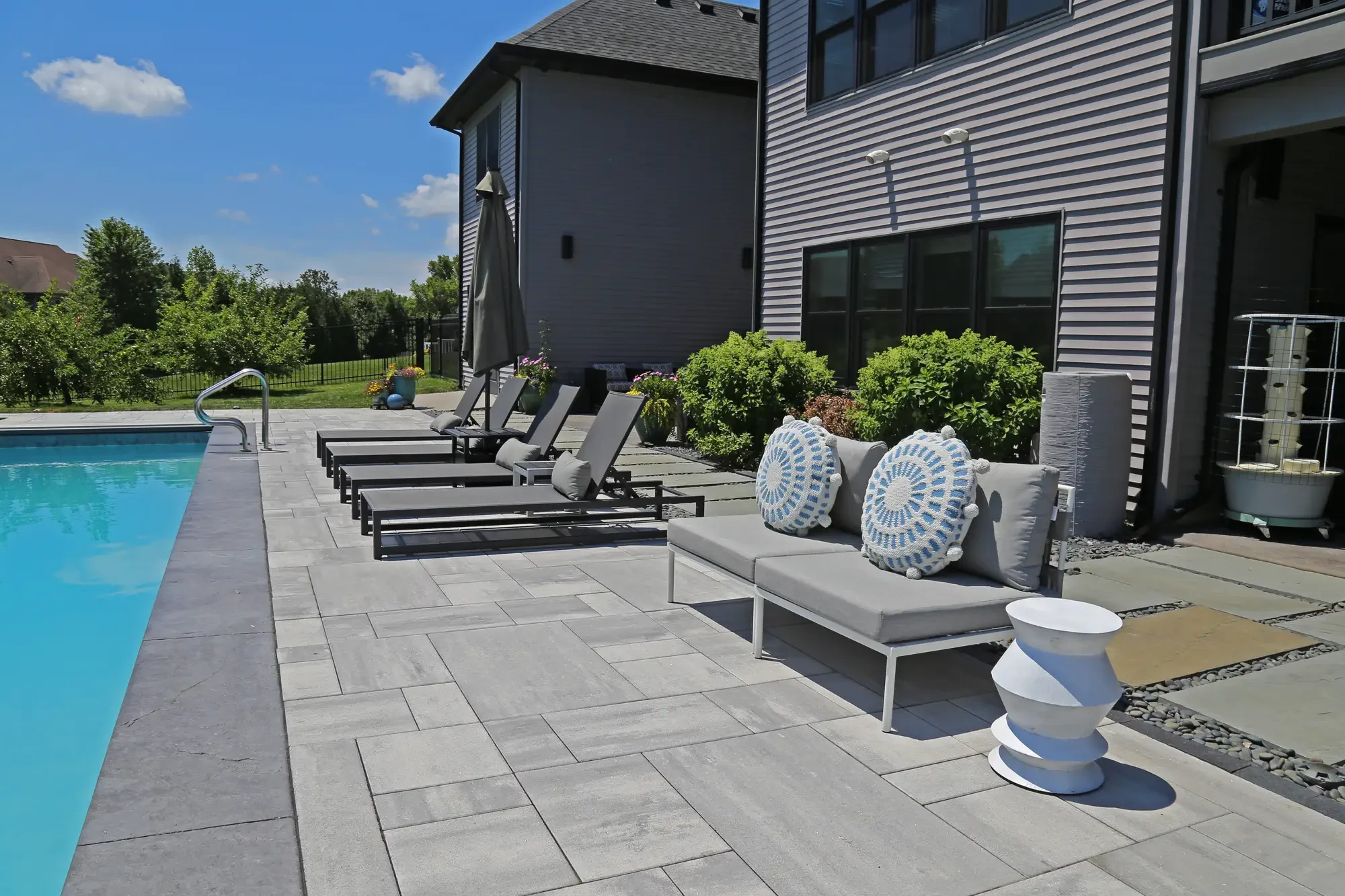Poolside chaise lounges and modern outdoor seating along large-format paver patio at Slate and Steel by Green View in Illinois