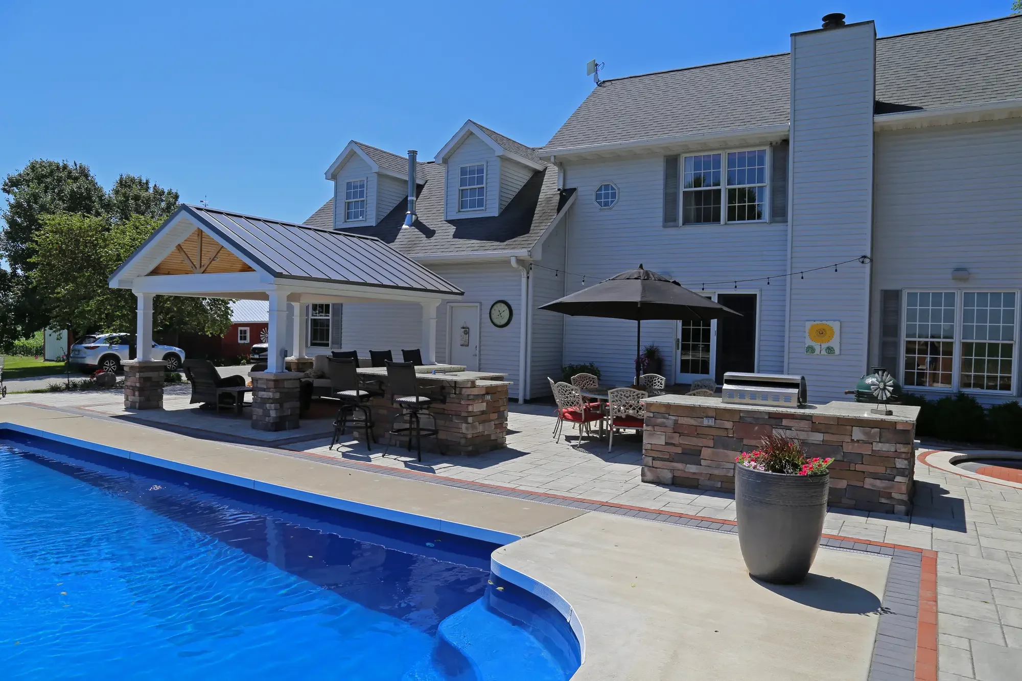 Full backyard view of pavilion, pool, and outdoor kitchen at The Prairie Pavilion by Green View in Illinois