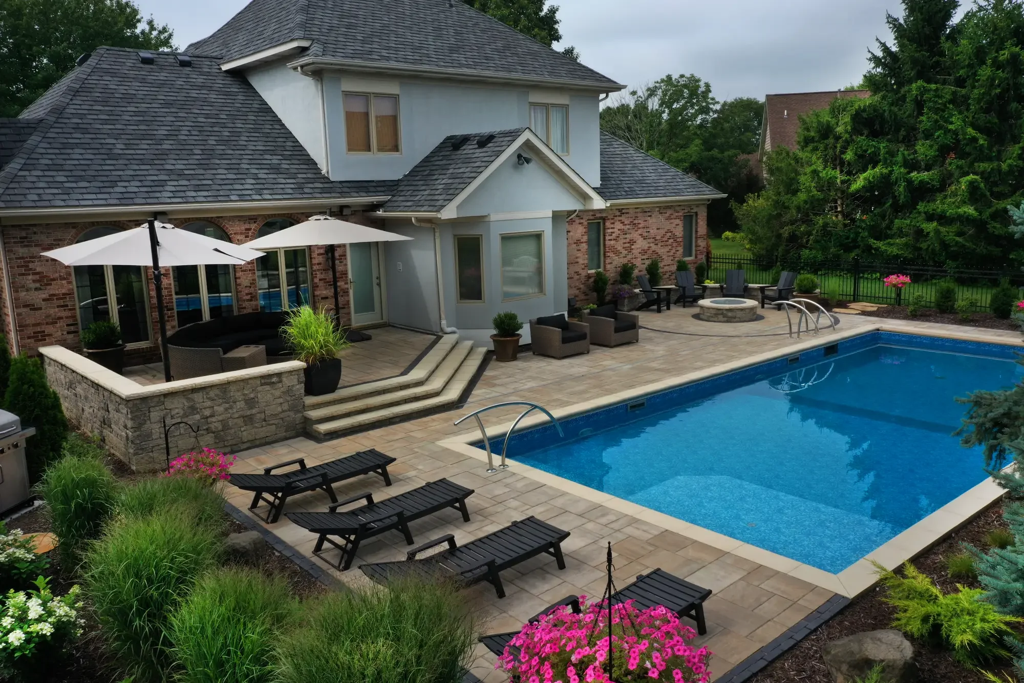 Aerial view of paver pool surround, raised stone terrace, and circular fire pit by Green View in Illinois
