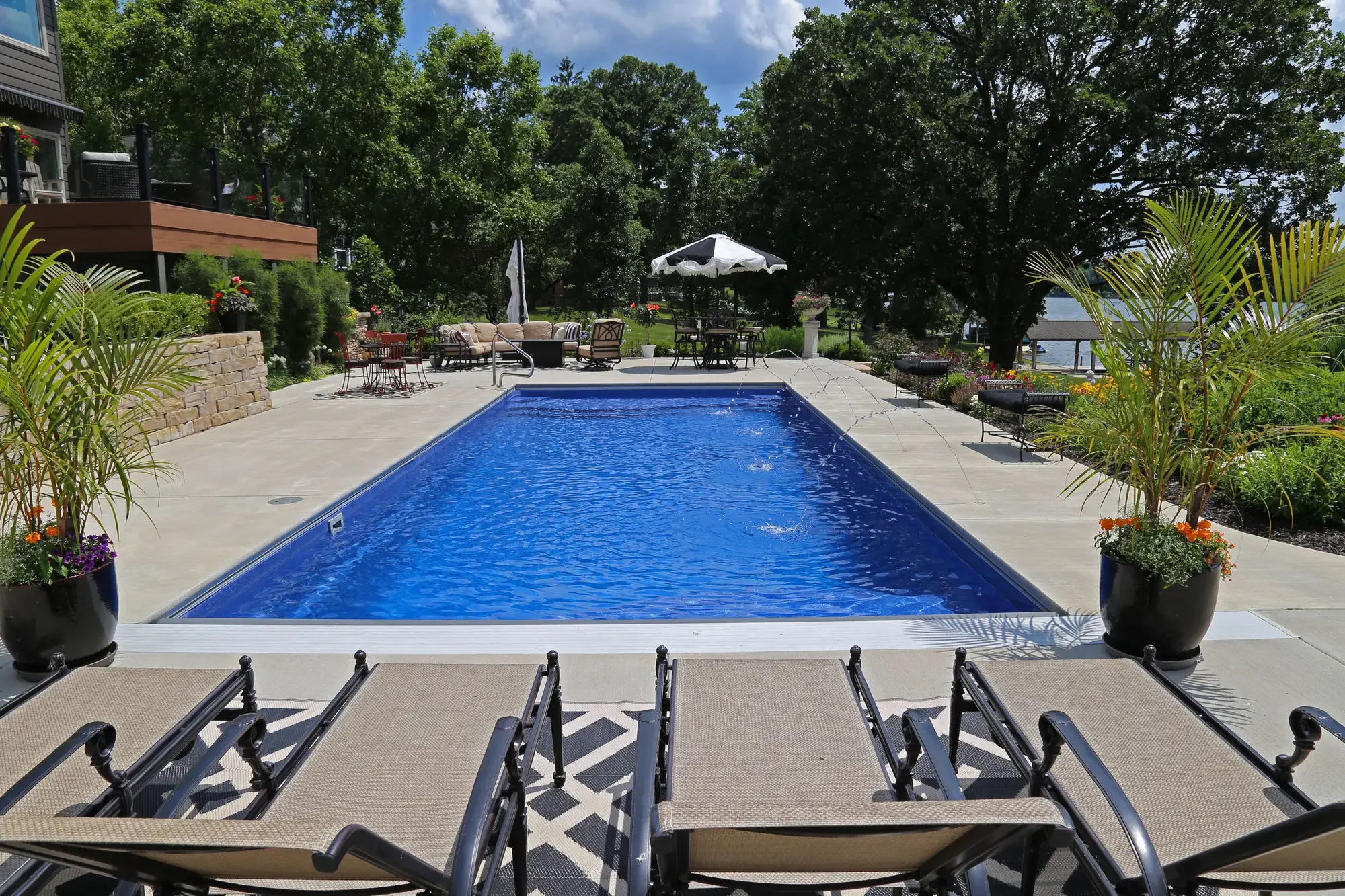 Rectangular pool with chaise lounges, tropical container plantings, and open lakefront view at The Lakeside Garden by Green View in Illinois