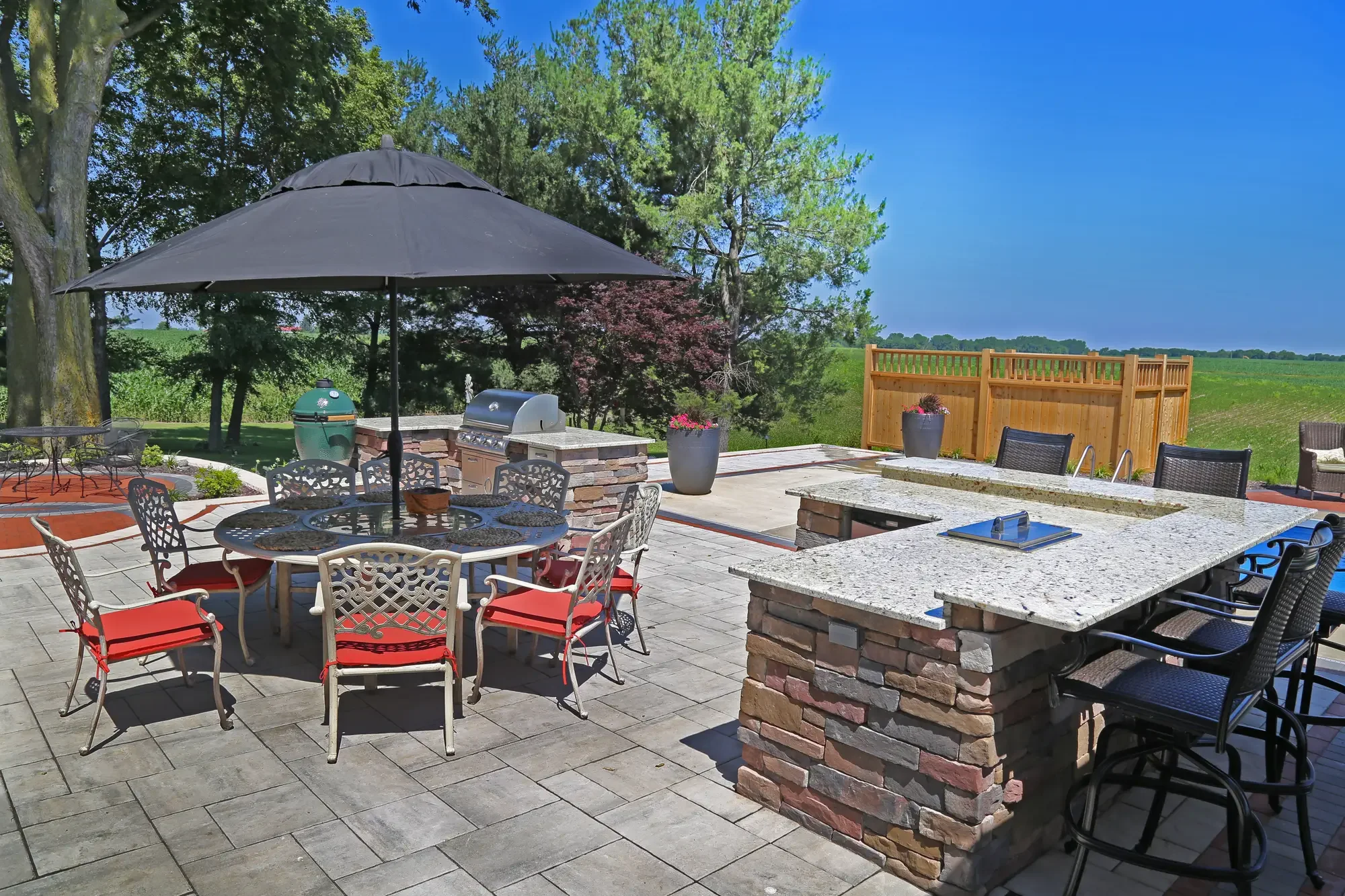 Outdoor kitchen with granite bar top, Big Green Egg, and dining area at The Prairie Pavilion by Green View in Illinois