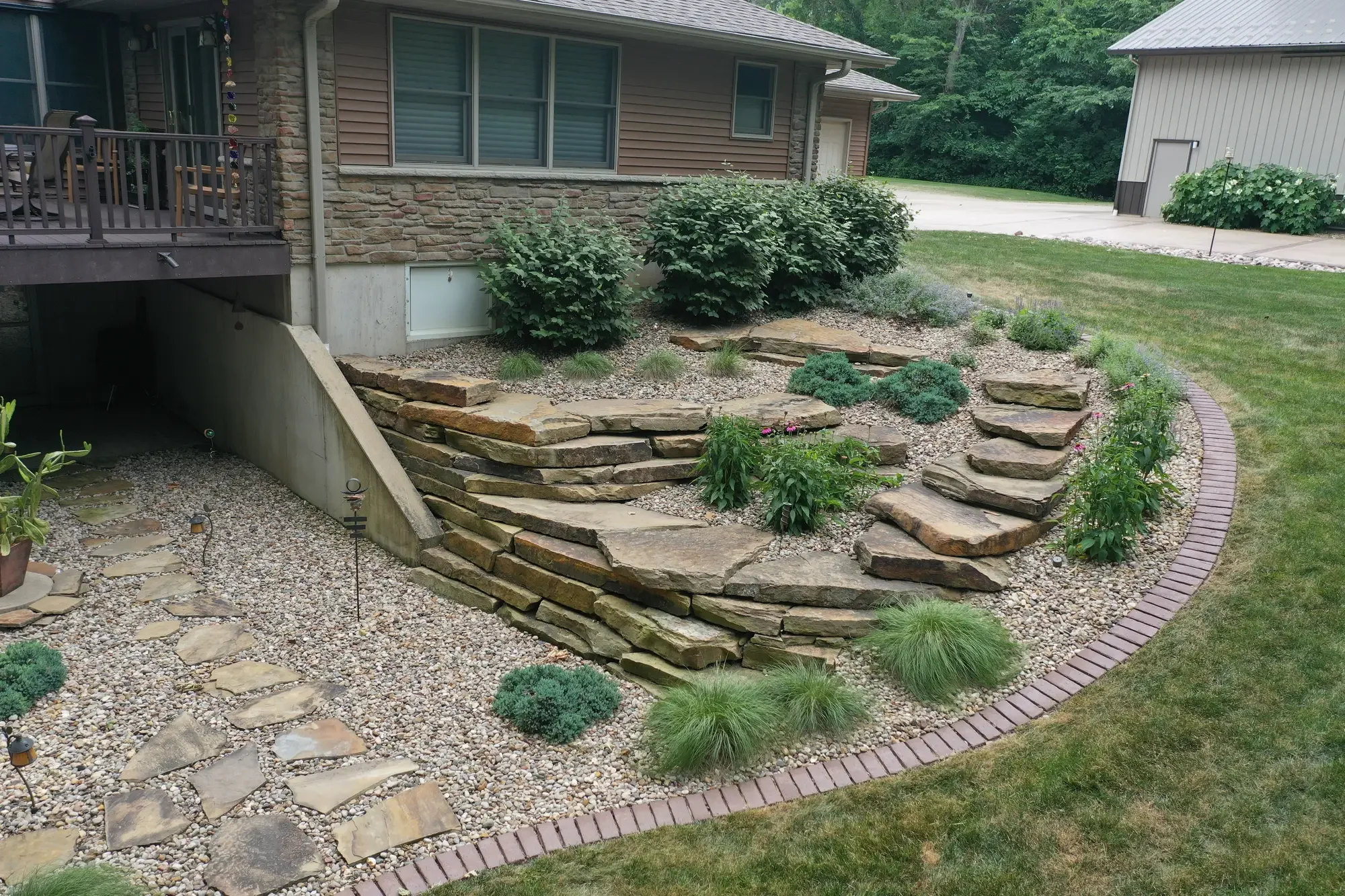 Flagstone retaining wall steps with gravel garden bed and ornamental plantings by Green View in Central Illinois