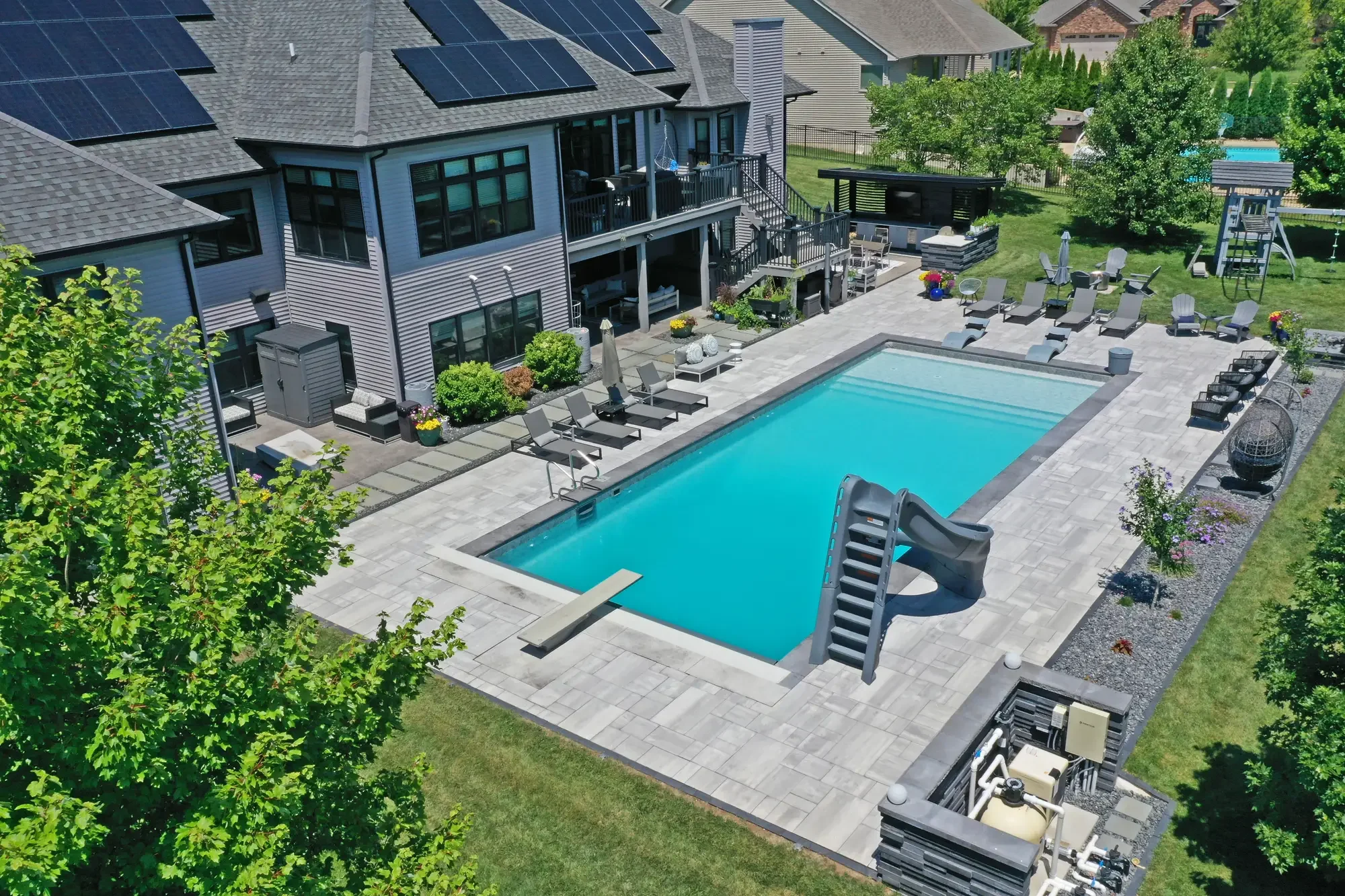 Aerial view of rectangular pool with water slide, diving board, and large-format paver surround at Slate and Steel by Green View in Illinois