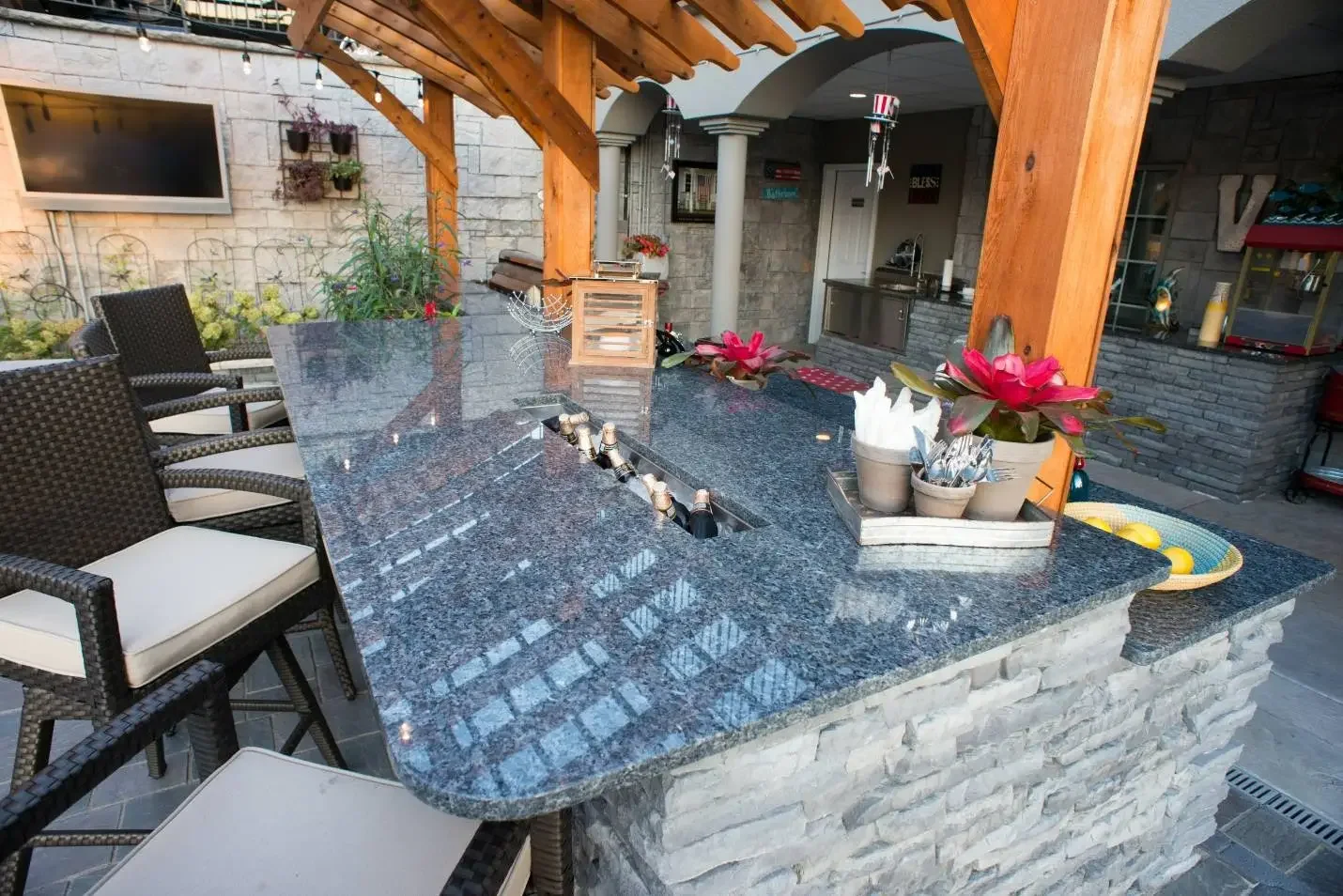 Close-up of granite bar top with built-in bottle chiller and wicker bar seating at The Craftsman's Retreat by Green View in Illinois