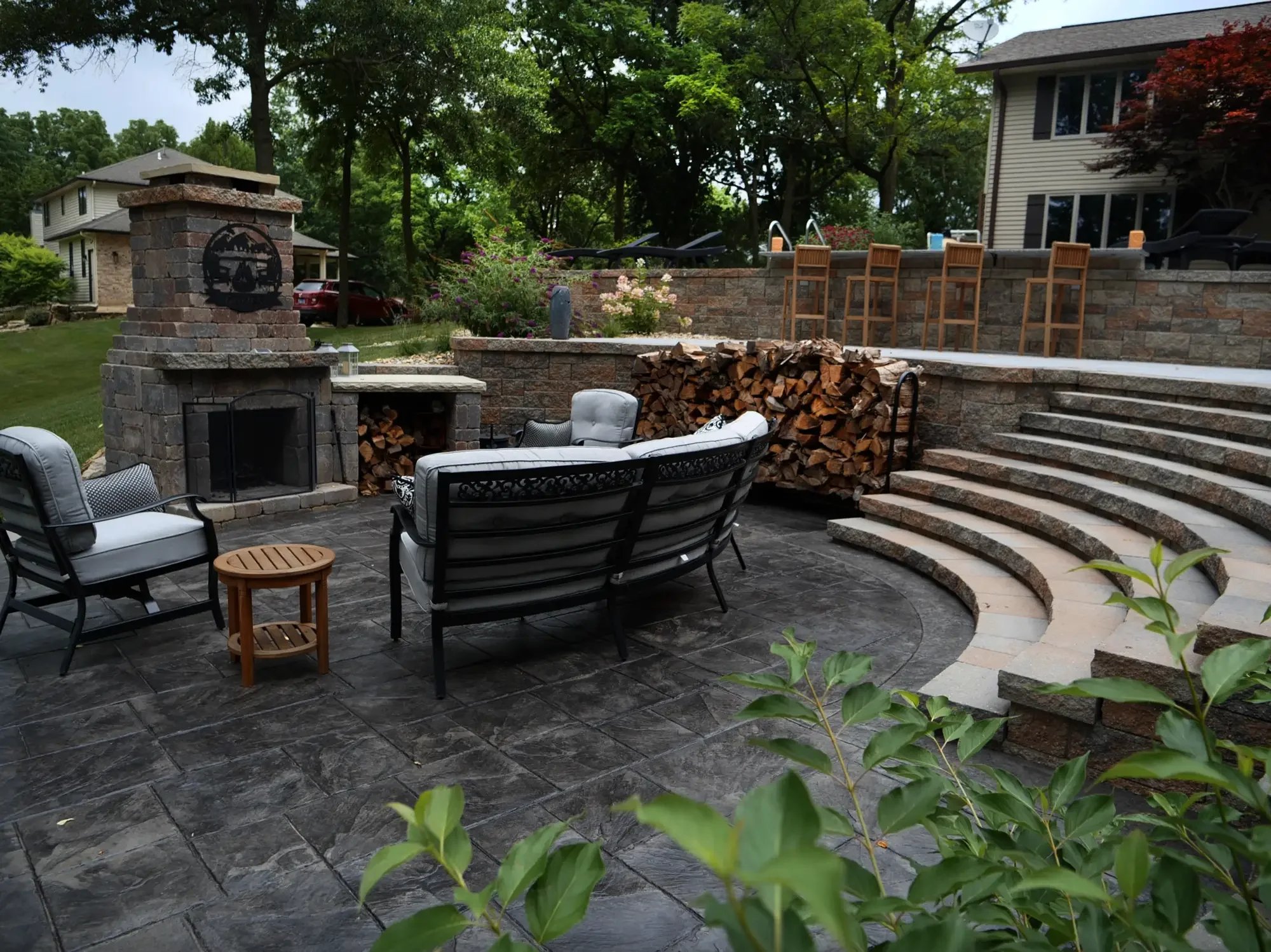 Stone outdoor fireplace and curved amphitheater steps with stamped patio at The Amphitheater by Green View in Illinois