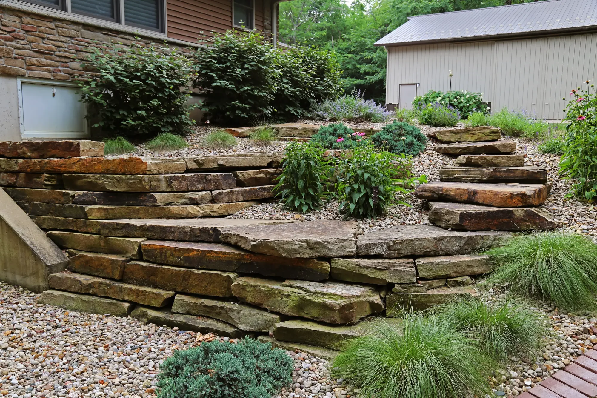Natural stone retaining wall steps with ornamental grasses and mixed garden plantings by Green View in Central Illinois