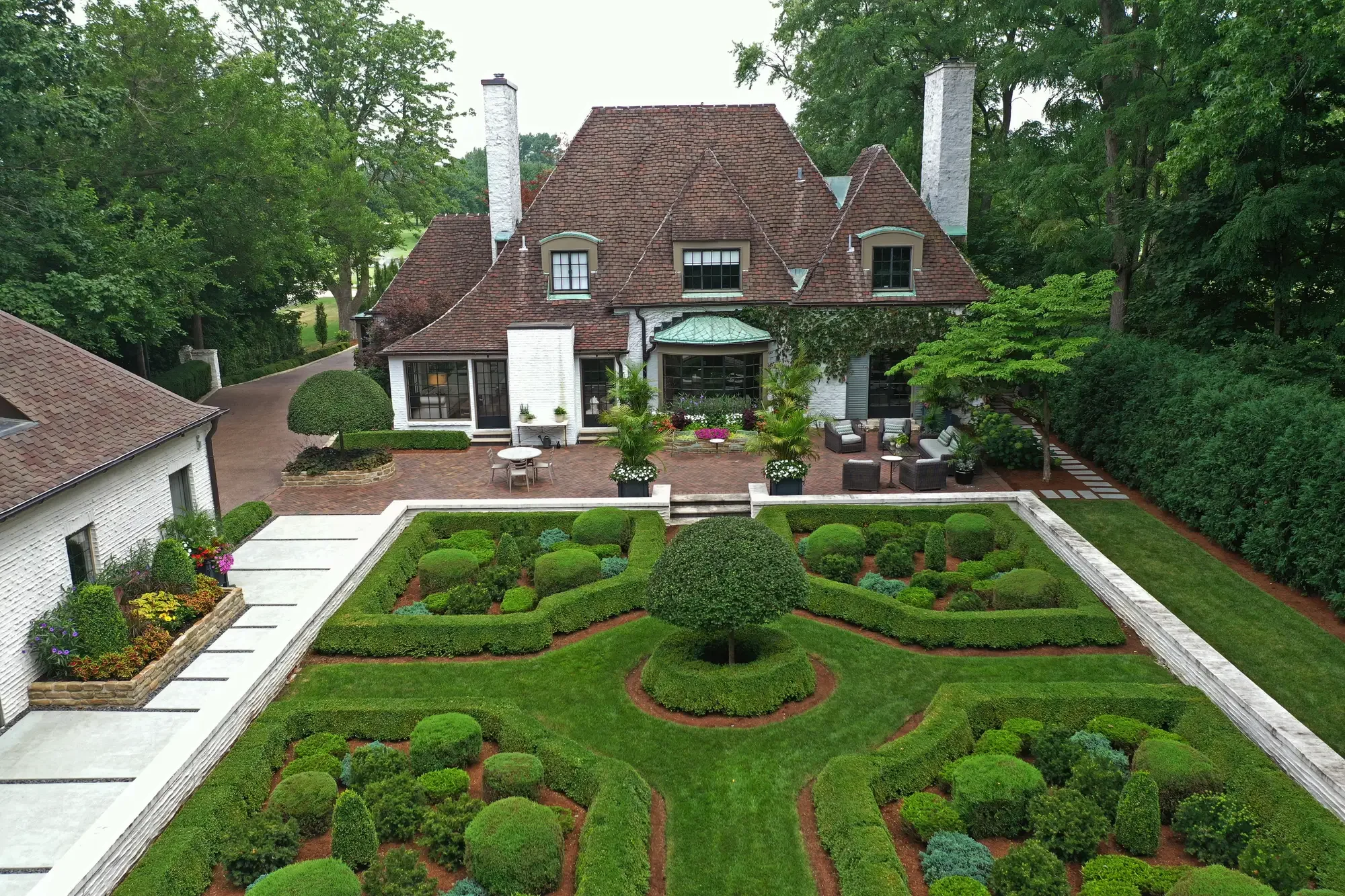 Aerial view of formal knot garden with clipped boxwood, central topiary, and brick patio at The Tudor Knot Garden by Green View in Illinois