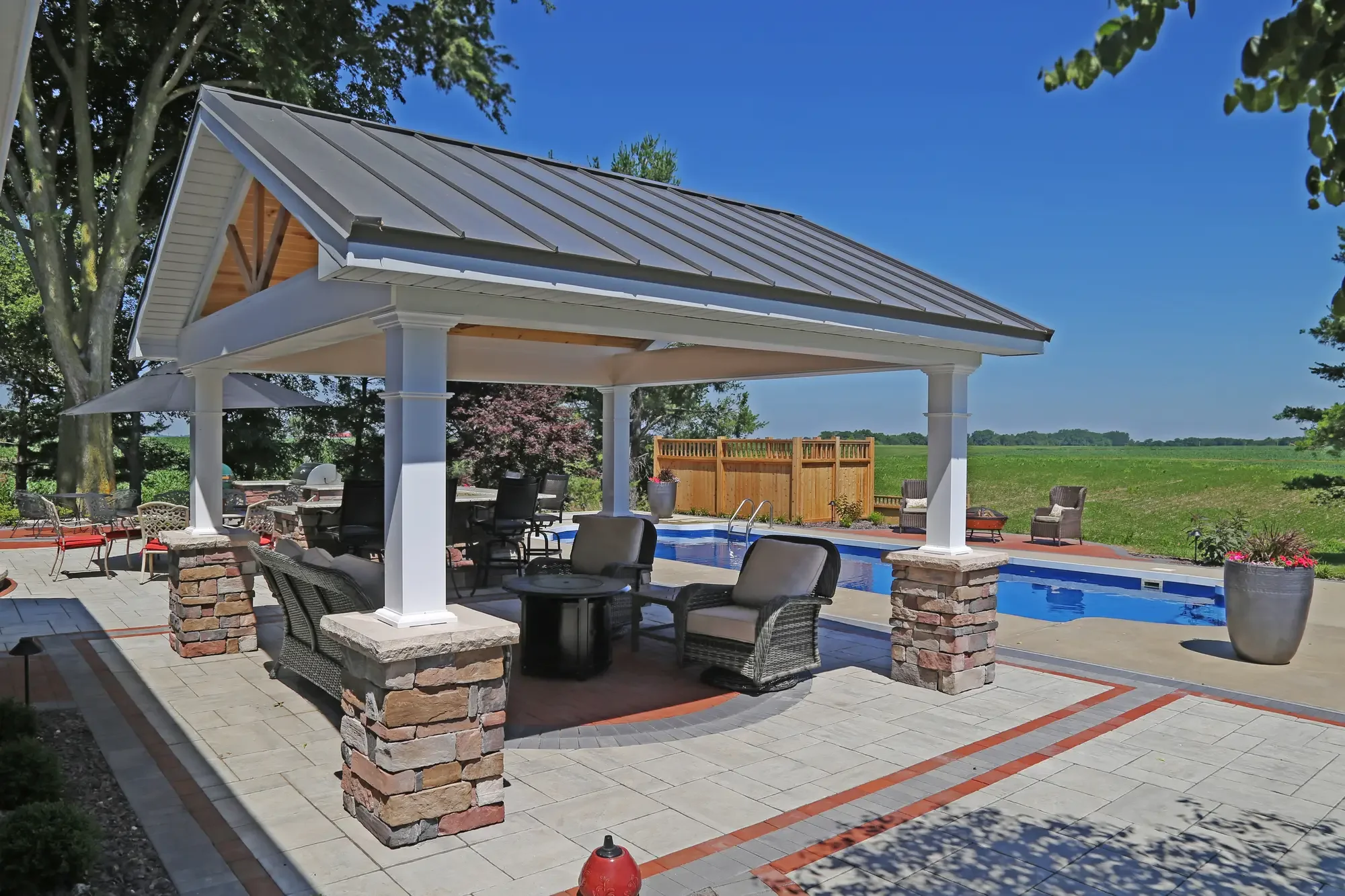 Metal roof pavilion with stone column bases and pool surround at The Prairie Pavilion by Green View in Illinois
