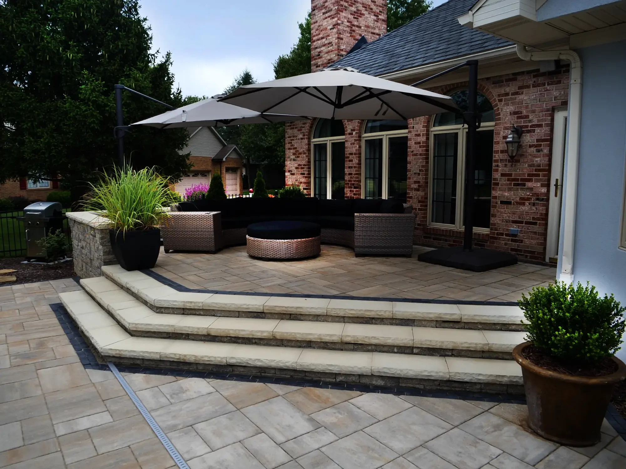 Raised paver patio with stone retaining wall and natural stone steps by Green View in Illinois