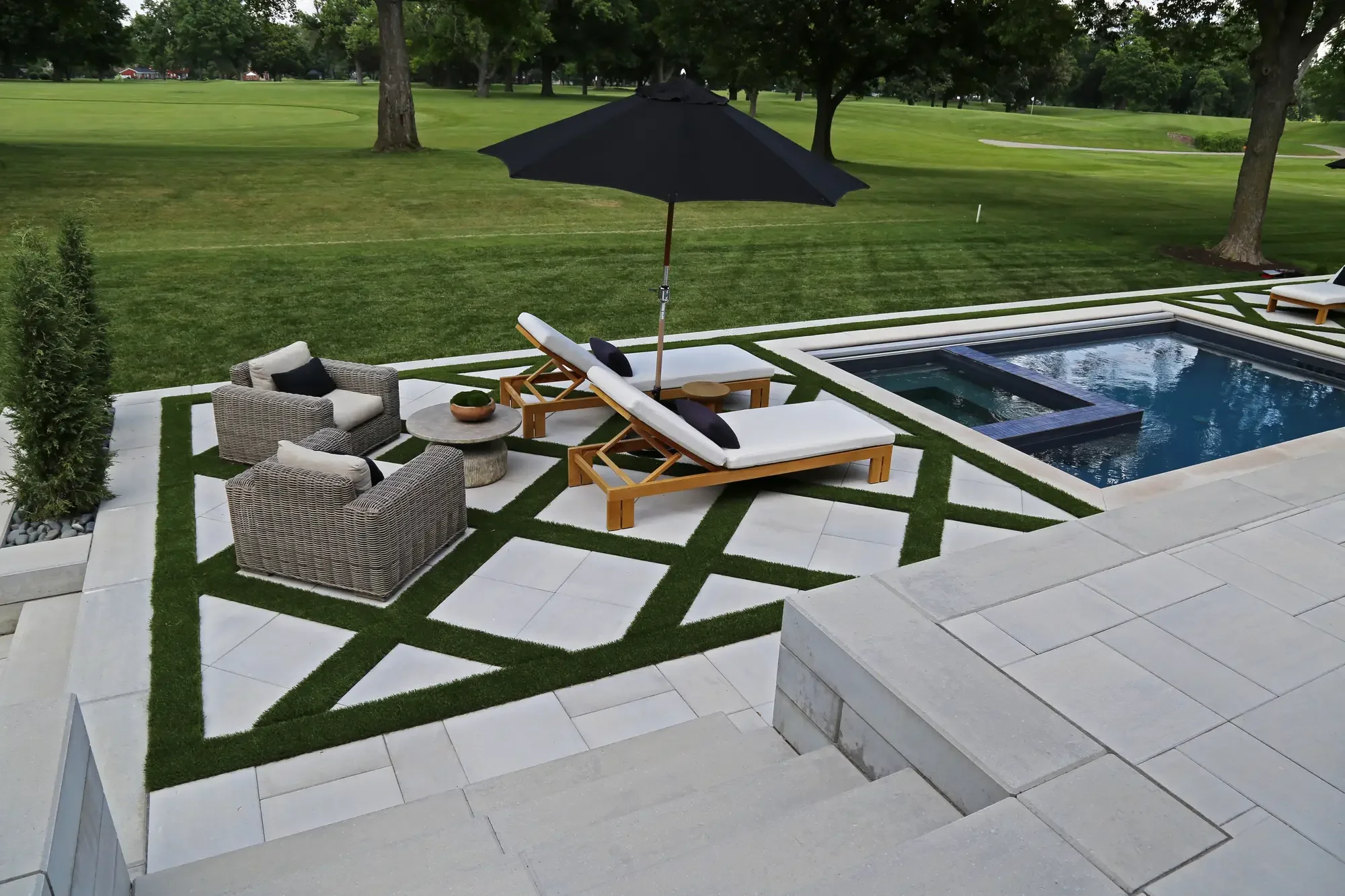 Poolside geometric turf-and-paver pattern with chaise lounges, wicker seating, and open golf course view at Geometric Oasis Retreat by Green View in Illinois