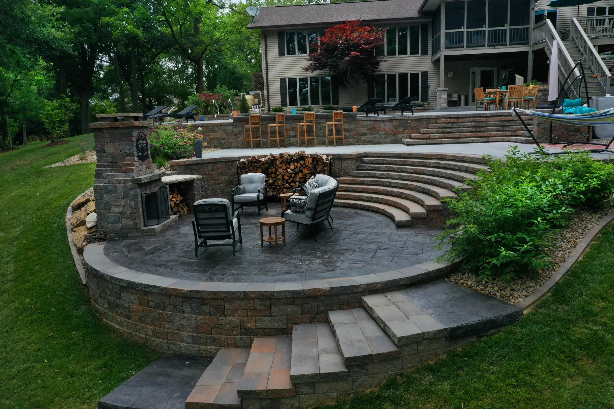Full view of curved stone amphitheater steps, outdoor fireplace, and pool surround at The Amphitheater by Green View in Illinoi