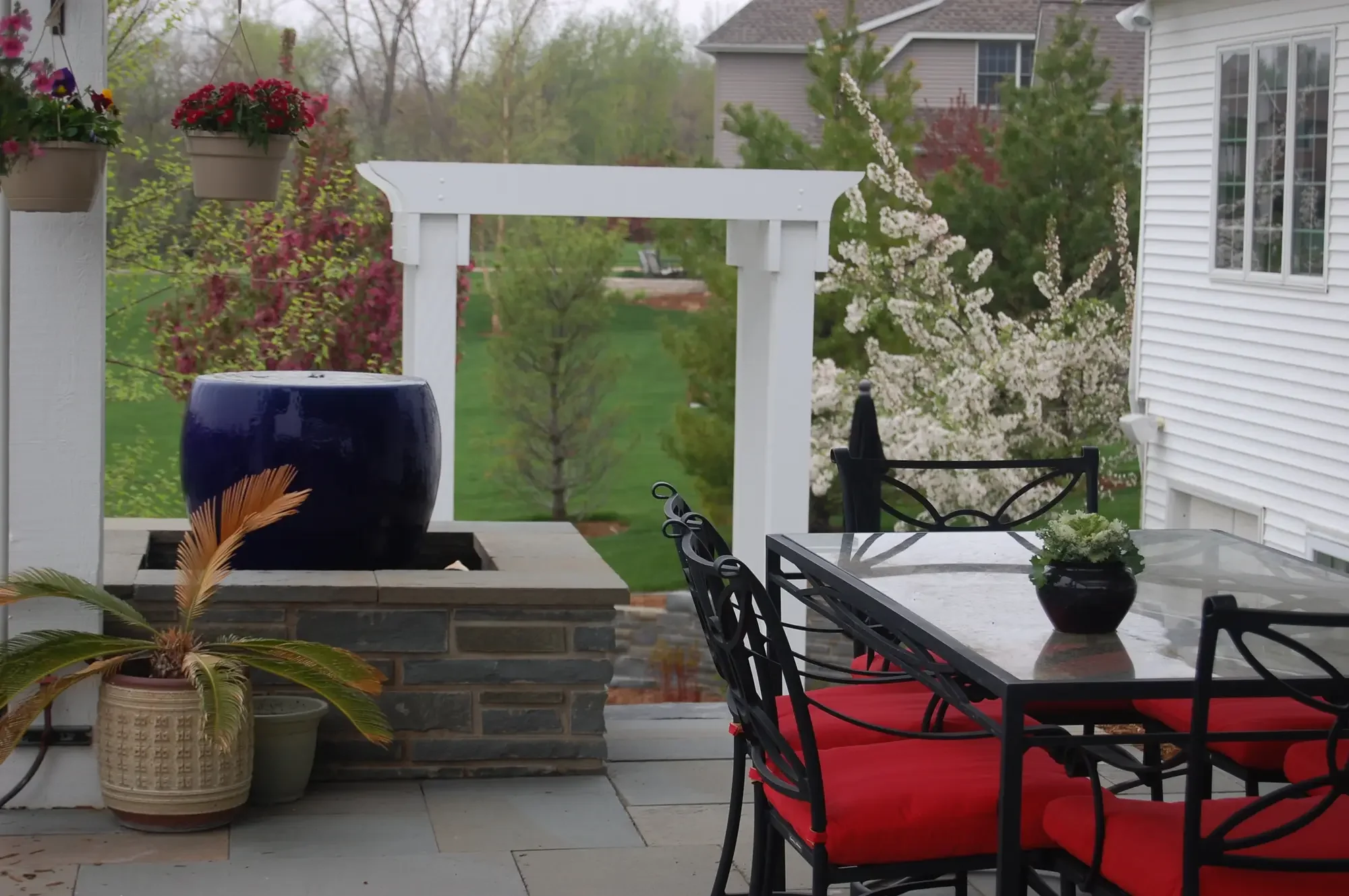 Upper bluestone patio with cobalt blue bowl water feature, white pergola, and spring flowering trees at Harmony in Stone and Water by Green View in Illinois