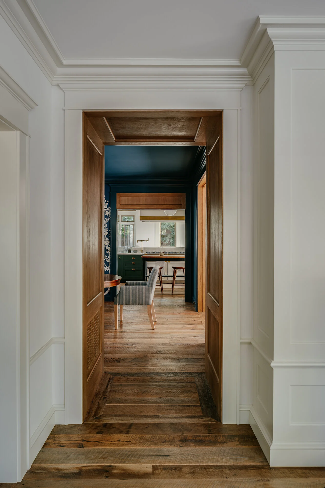 Centuries-old reclaimed white oak flooring in Palo Alto Craftsman home vestibule with custom stained wood trim and painted millwork by Holler Architects