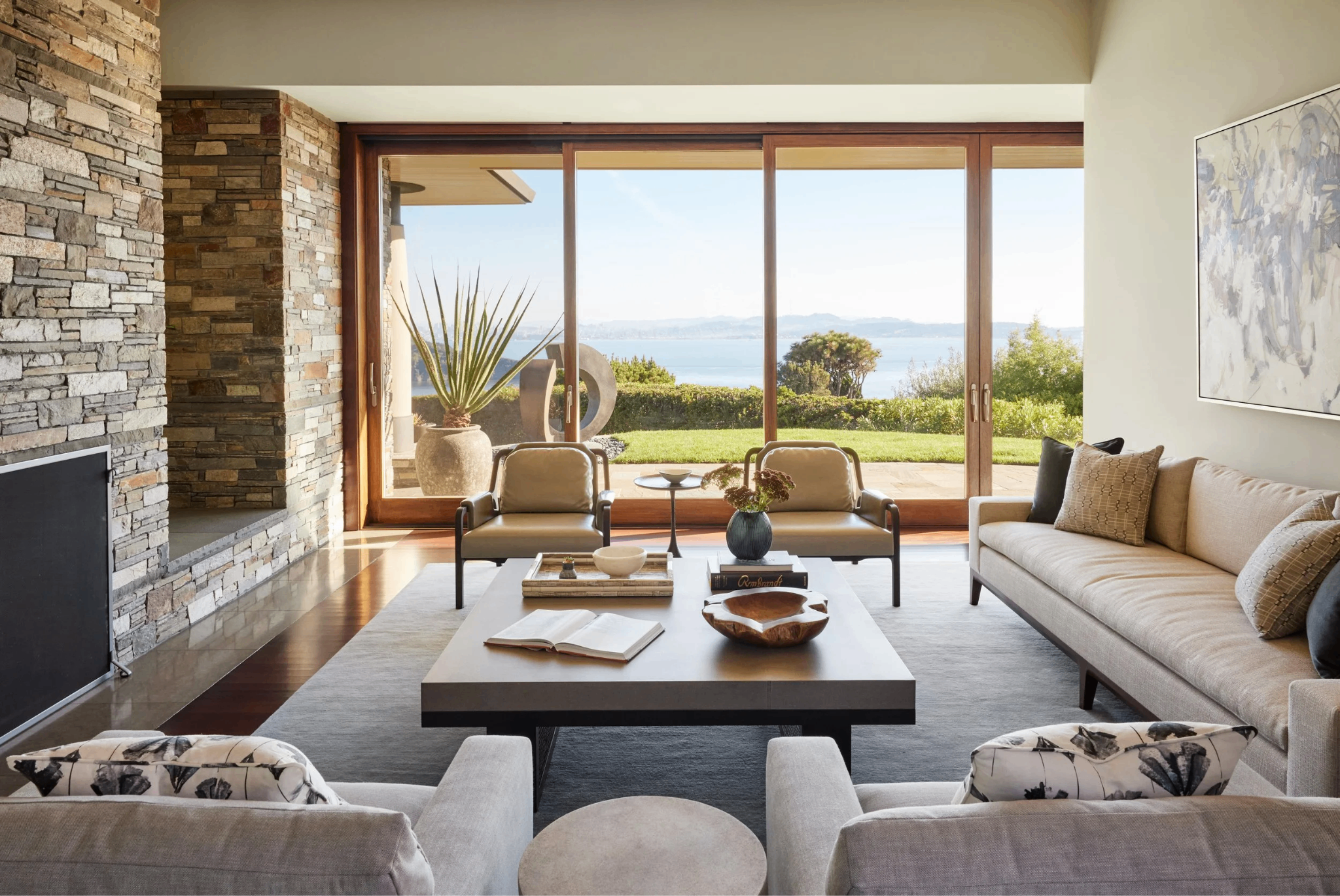 Mid-century modern living room with stacked stone fireplace and walls of glass framing a San Francisco Bay view