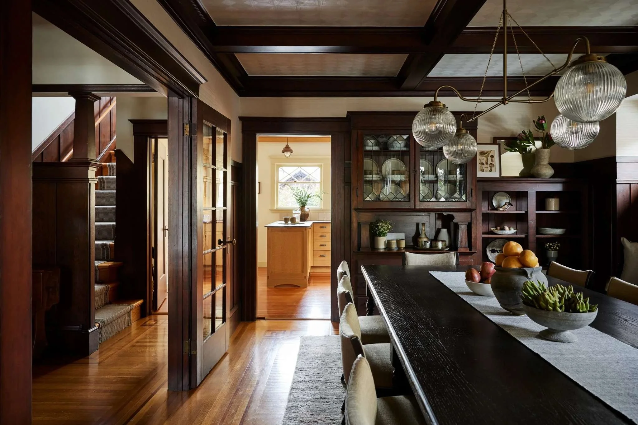 Craftsman dining room with dark wood coffered ceiling, leaded glass built-in hutch, and glass globe pendant lighting