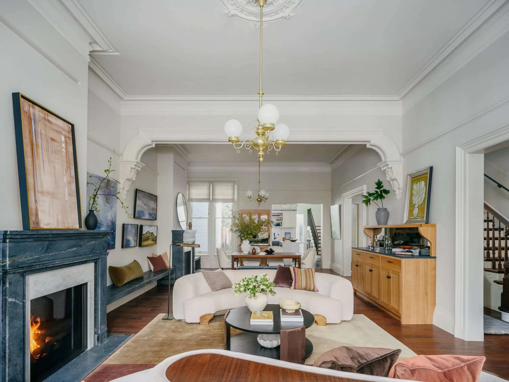 San Francisco Victorian living room with carved marble fireplace, ornate crown molding, and brass globe chandelier