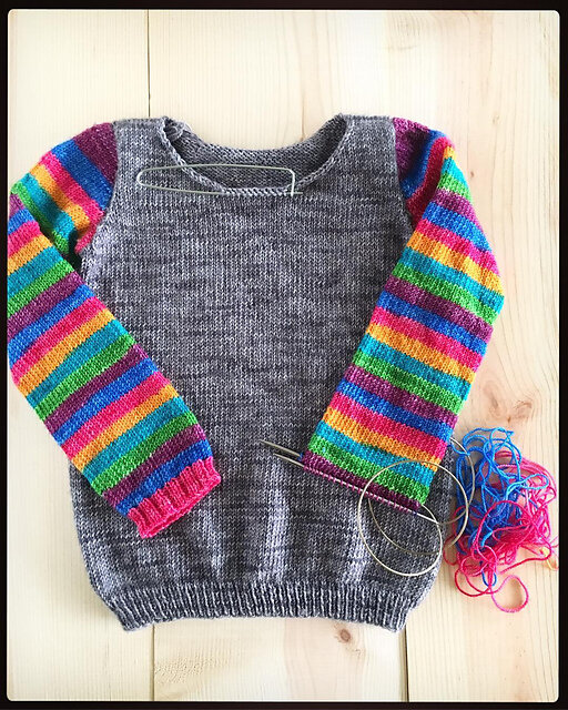 Nearly finished child’s sweater with grey body and purple/blue/pink/yellow/turquoise/green striped arms. © &amp; knit by&nbsp;Knitterly Things