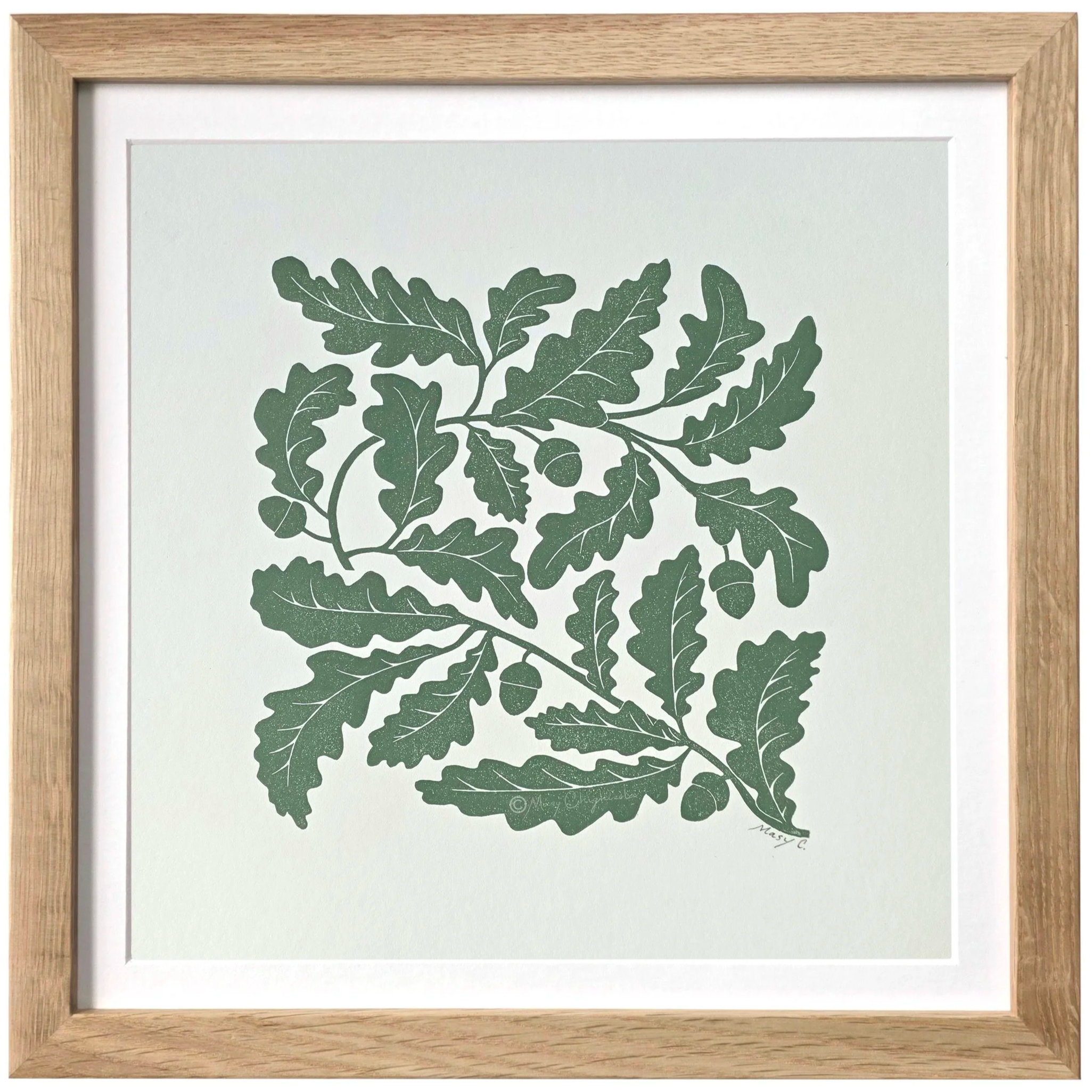 Nature-inspired 12x12 original block print featuring an oak tree branch with detailed leaves and acorns, hand printed in olive green ink on off-white fine art paper and framed in light wood.