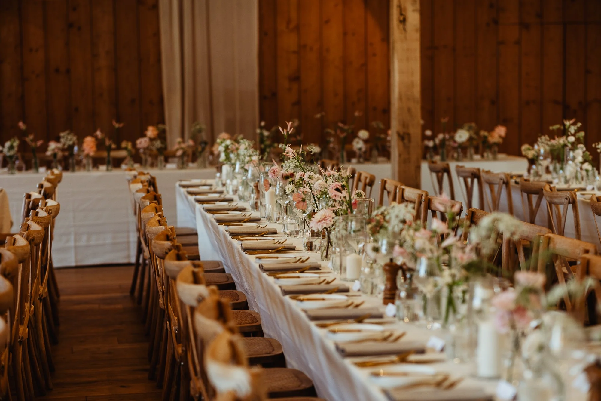 Long dining table decorated for a formal event with floral budvases and tableware, at Worstead Estate wedding venue in Norfolk. Created by local luxury florist.