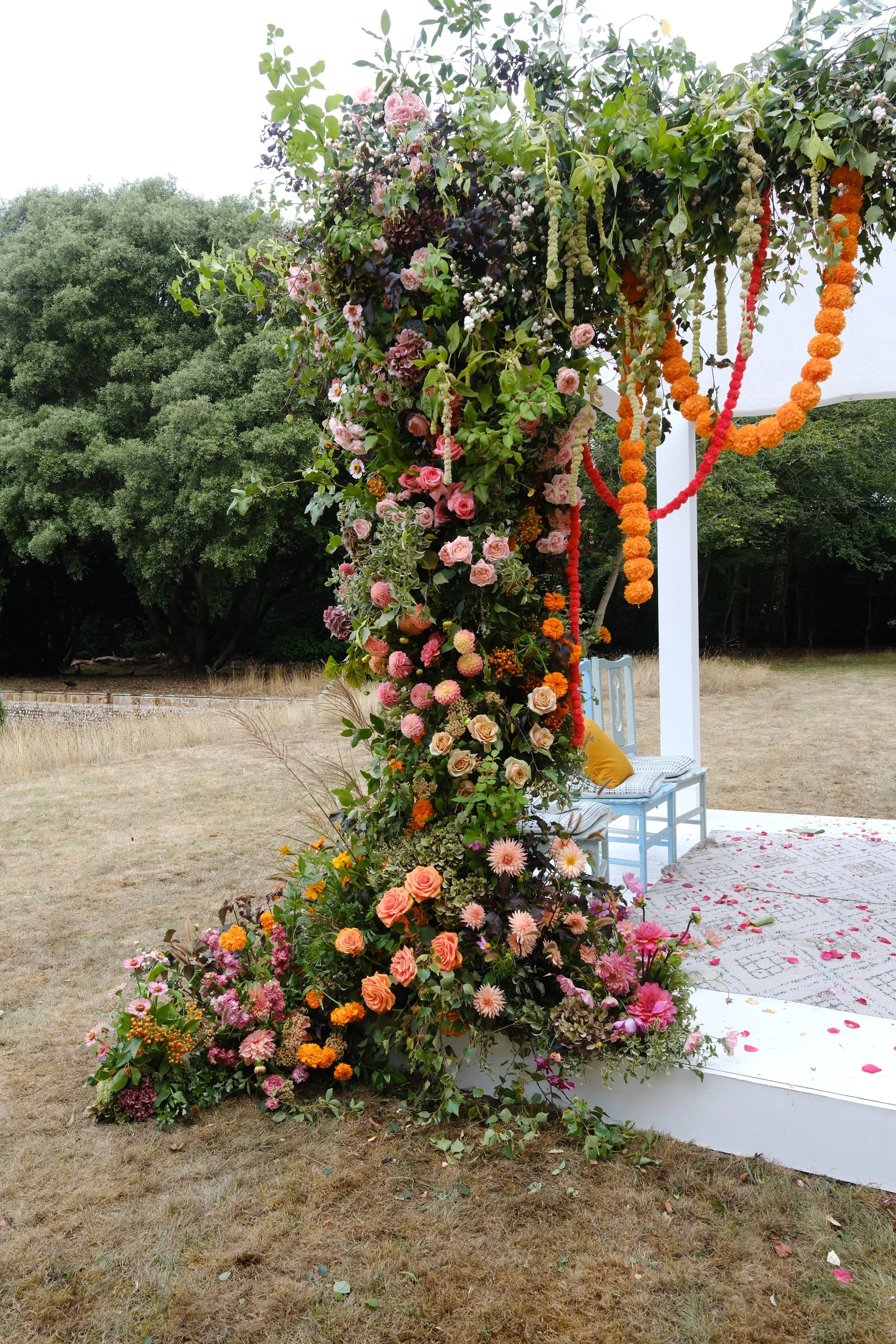 A Mandap decorated with traditional colourful blooms for a Hindu fusion wedding at Voewood house in Norfolk.