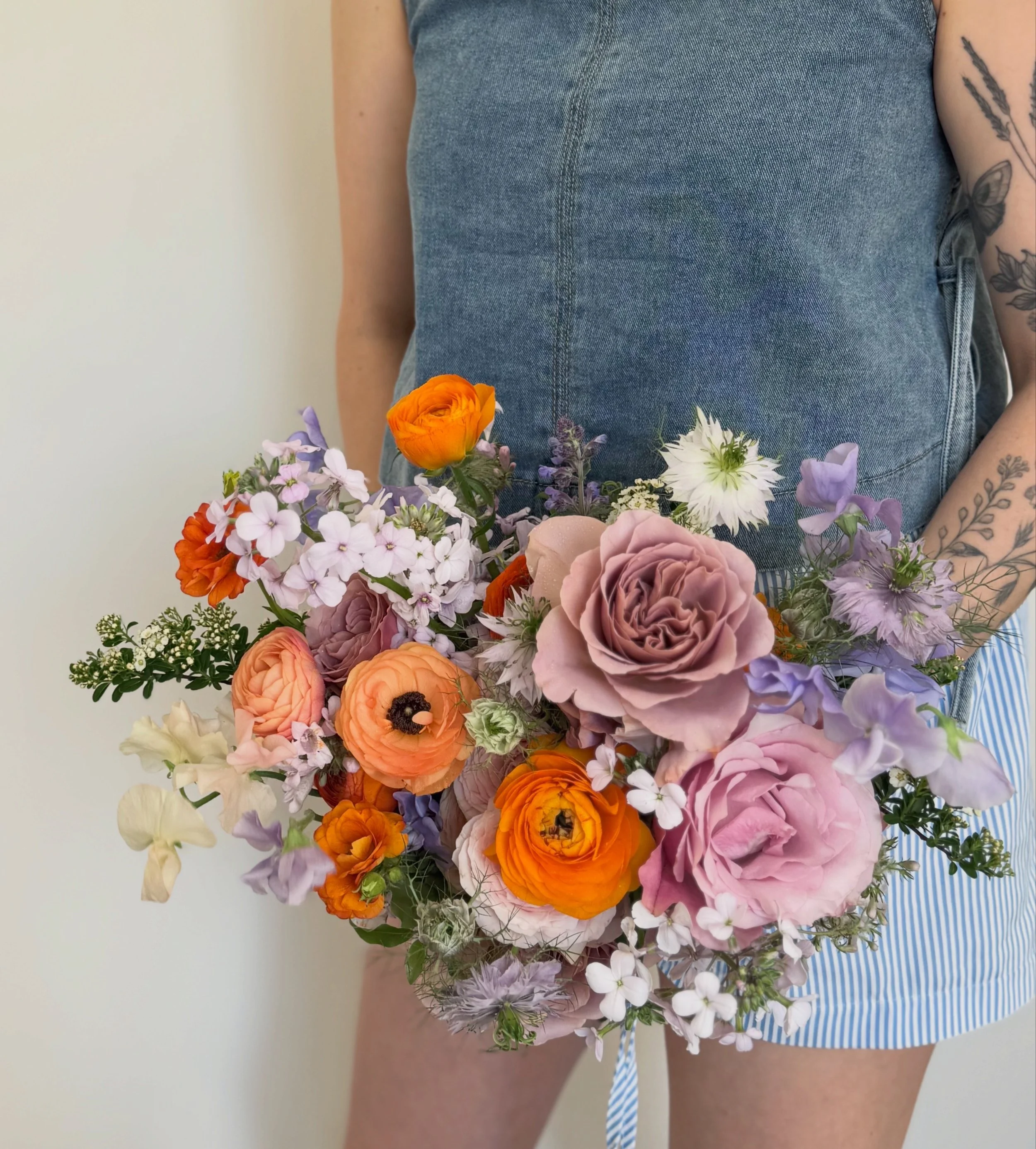 A just gathered, natural and whimsical bridal bouquet in zesty oranges and soft lilacs.
