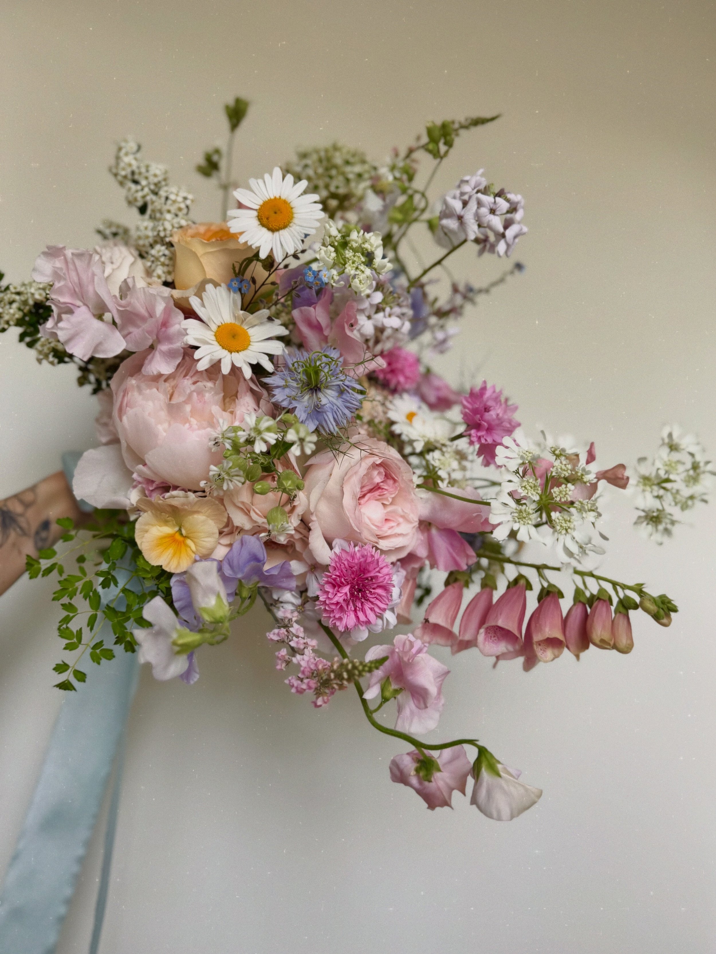 A fun, natural and whimsical bridal bouquet, brimming with seasonal flowers of all sorts of textures and forms
