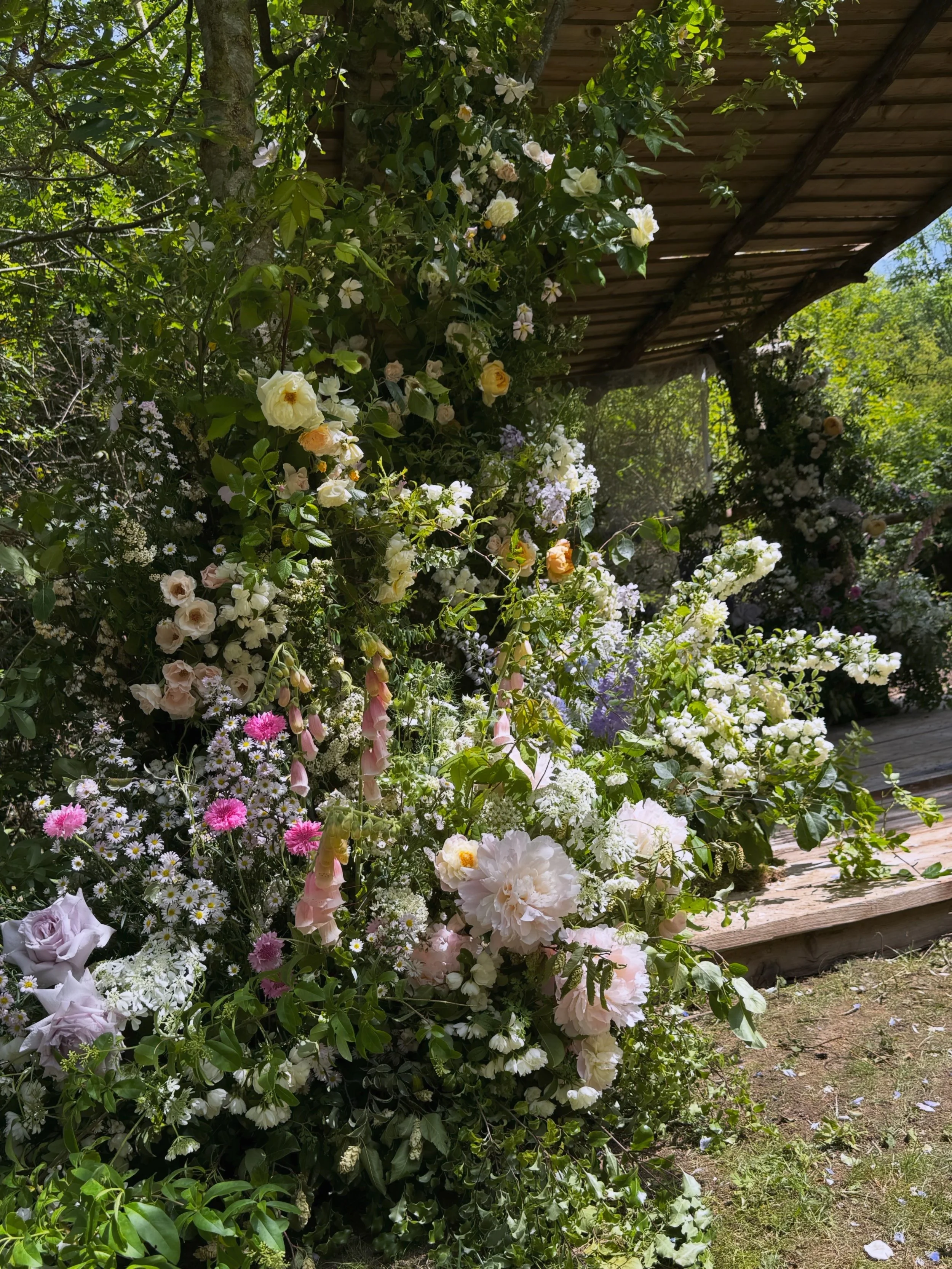 A luxury floral installation for a woodland wedding in farmland, Norfolk. A kaleidoscope of garden blooms created by a luxury, renowned florist, Bracken and twine flowers 
