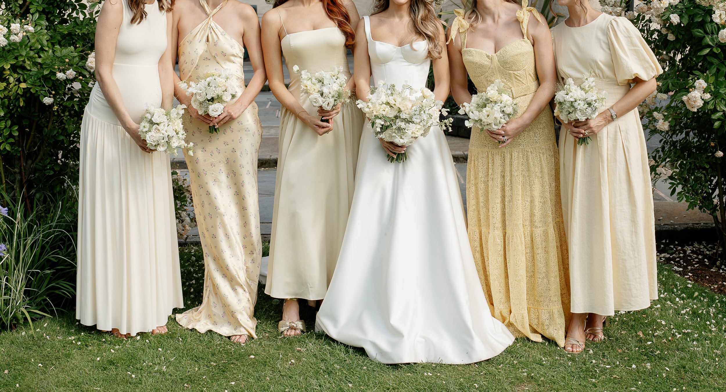 Group of women in pastel-coloured dresses holding chic bouquets, for an outdoor wedding in Norfolk. Photographer is the best Sharon Cudsworth 