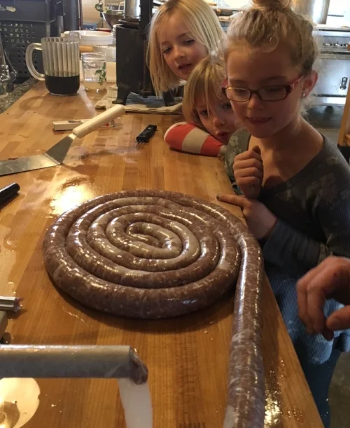 Lola, Ainsley and Imogen Barsotti watch the venison sausage get stuffed into hog casings.