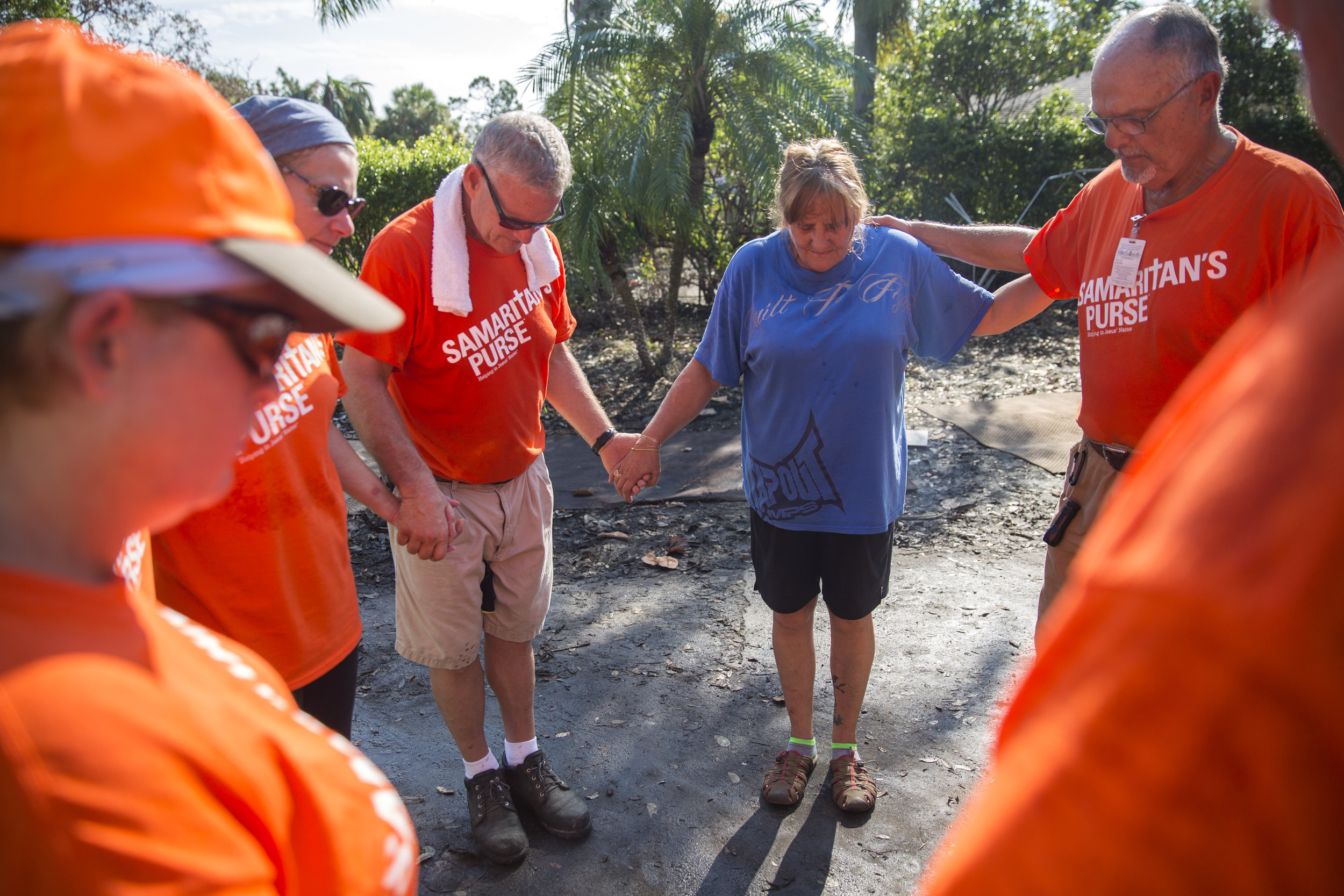  Lori Malone is joined in prayer by volunteers from Samaritan's Purse humanitarian aid outside of her damaged home in Bonita Springs on Tuesday September 26, 2017. Malone was finally able to begin clearing out the interior of her house this week, whi