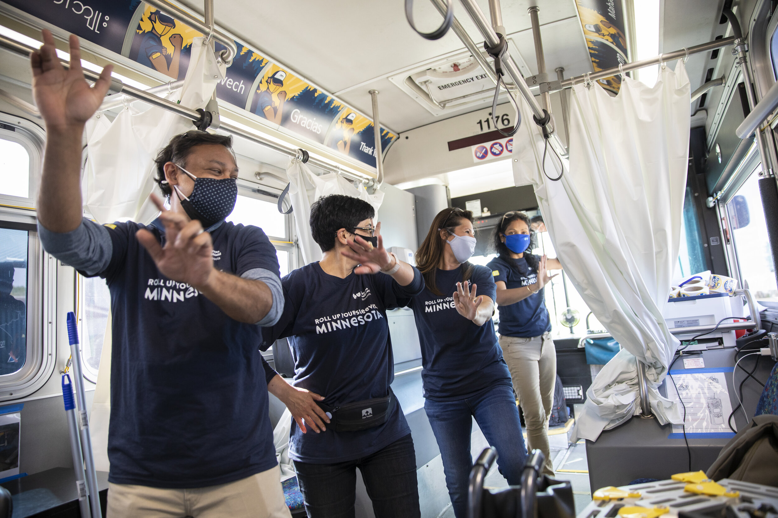  Blue Cross and Blue Shield of Minnesota staff volunteers dance together aboard the mobile Covid-19 vaccine clinic to celebrate their day of work. (Liam James Doyle for The New York Times) 