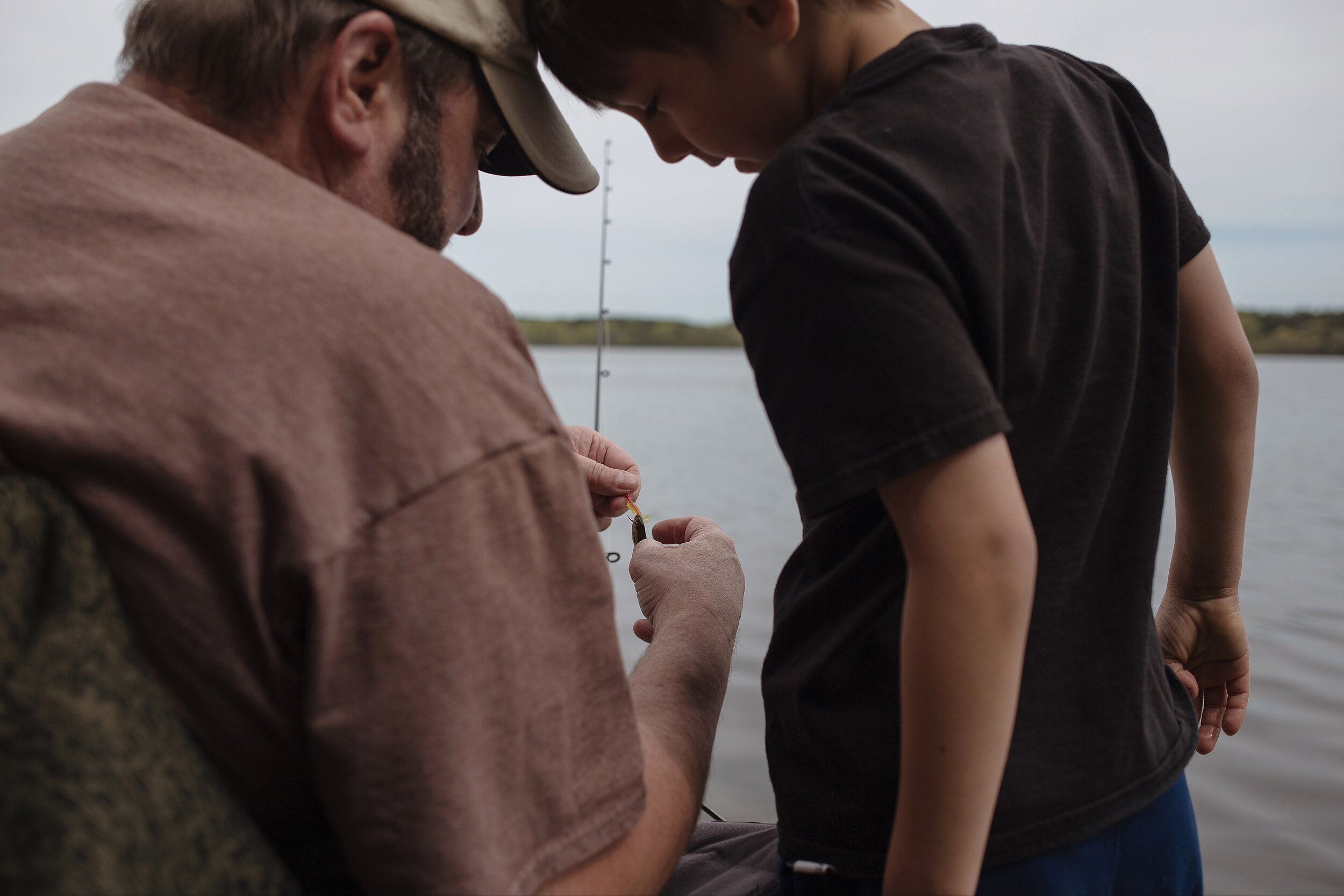  Mike Hoey (left) of Anoka helps his grandson, Hunter Johnson, showing him how to properly bait his fishing hook at Vadnais Lake near St. Paul for the Minnesota fishing opener on Saturday, May 12, 2018. For MPR News. 